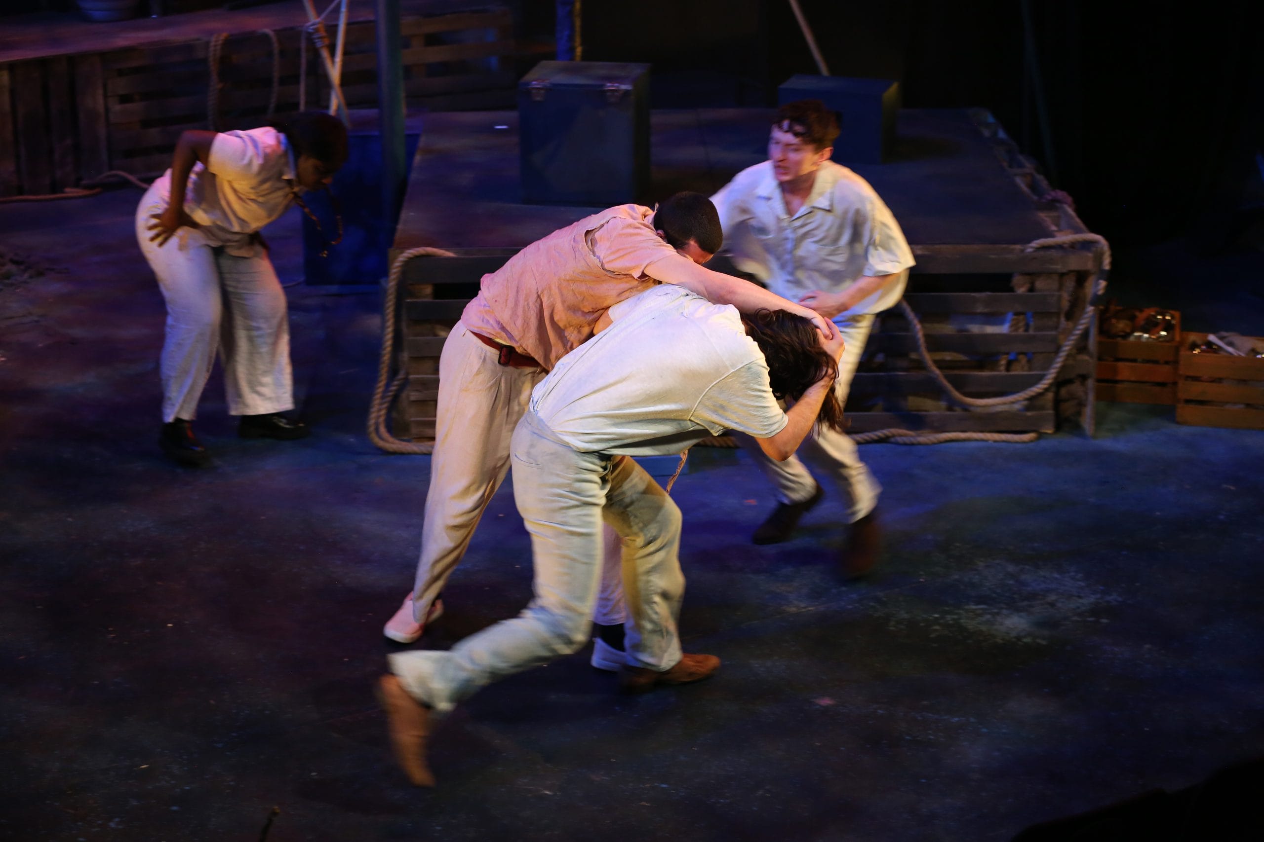 two actors wrestle whilst another runs in to stop them;