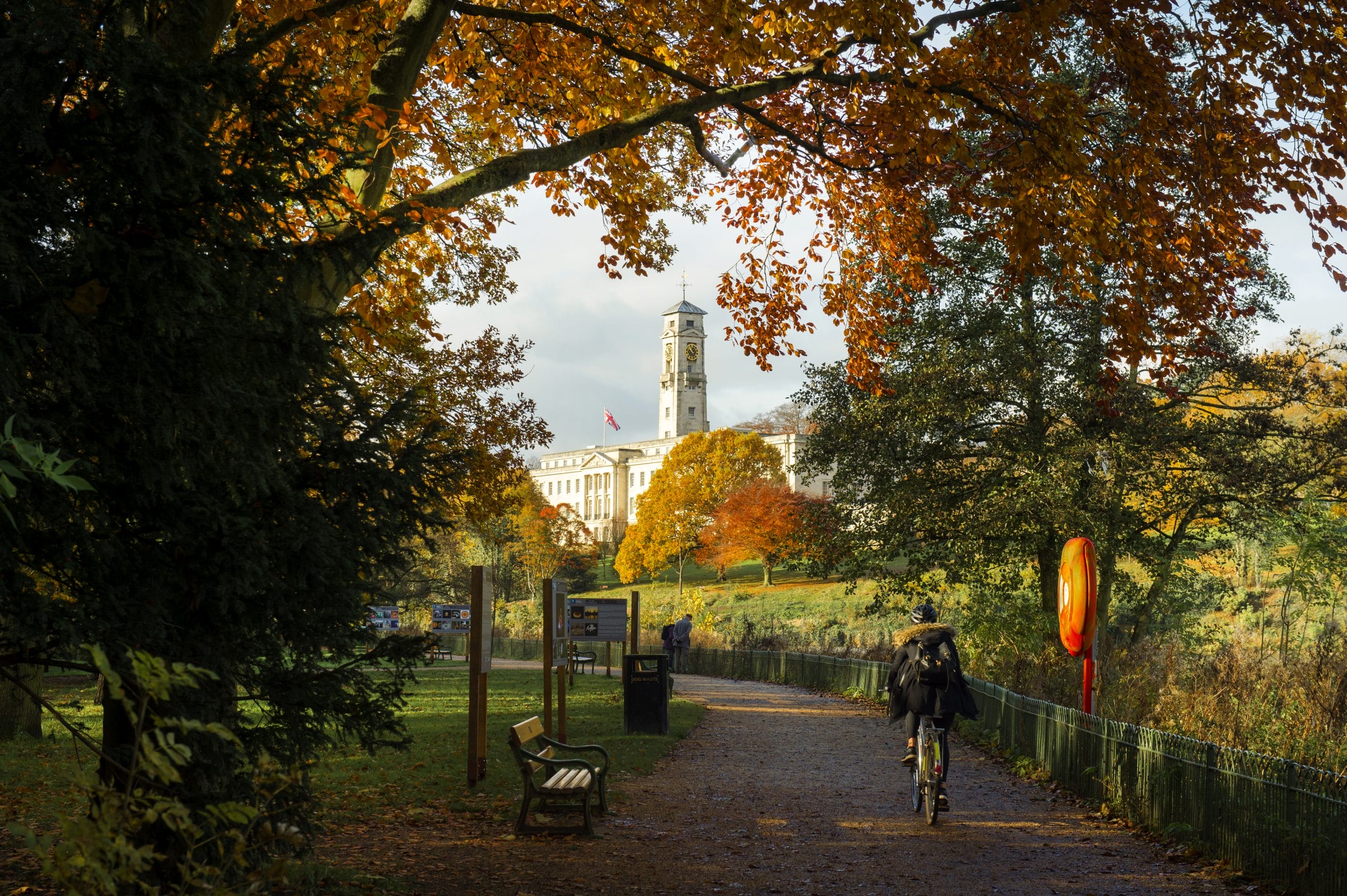 A person walks between Autumnal trees with UoN trent building in the background