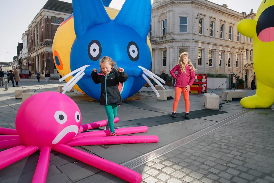 Children jump over an inflatable pink octopus and blue bunny