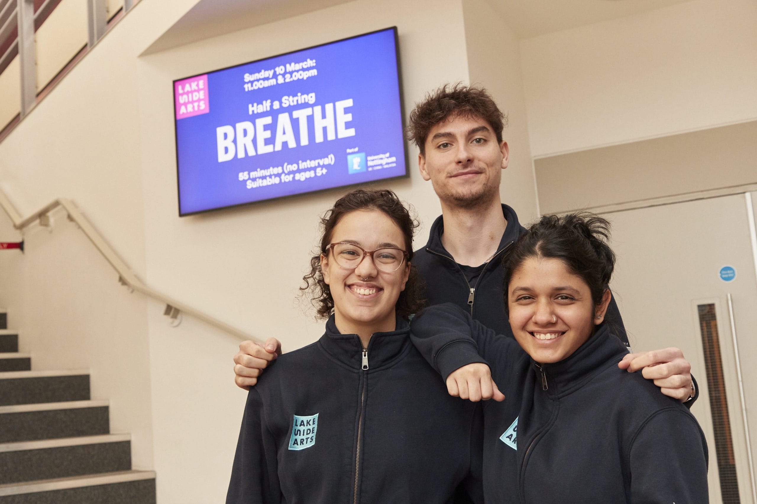 Lakeside front of house staff in blue fleeces stand smiling