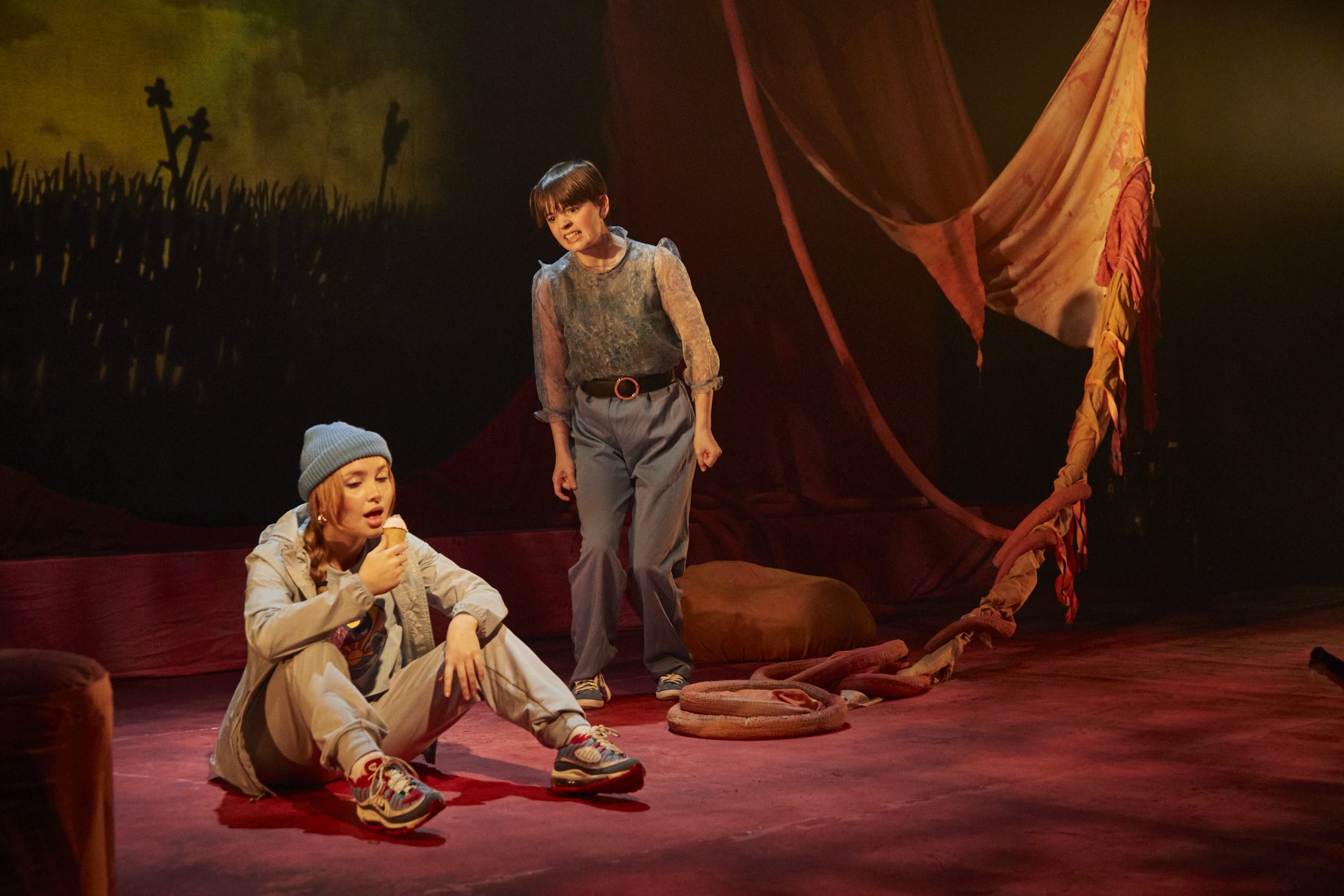 an actor stands up yelling at an actor sat on the floor looking uninterested