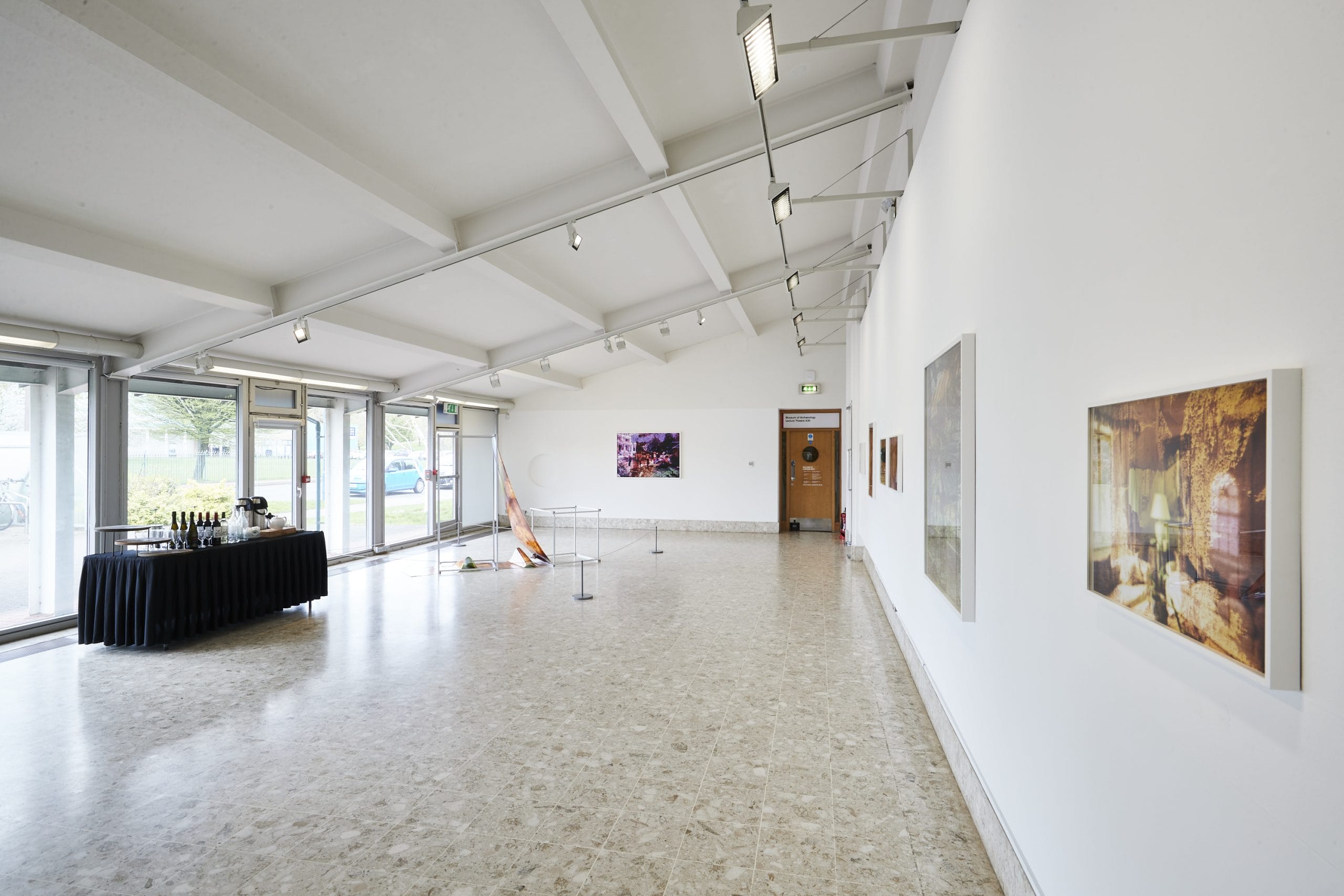 A gallery space with a big window and a sofa looking at artworks on the walls