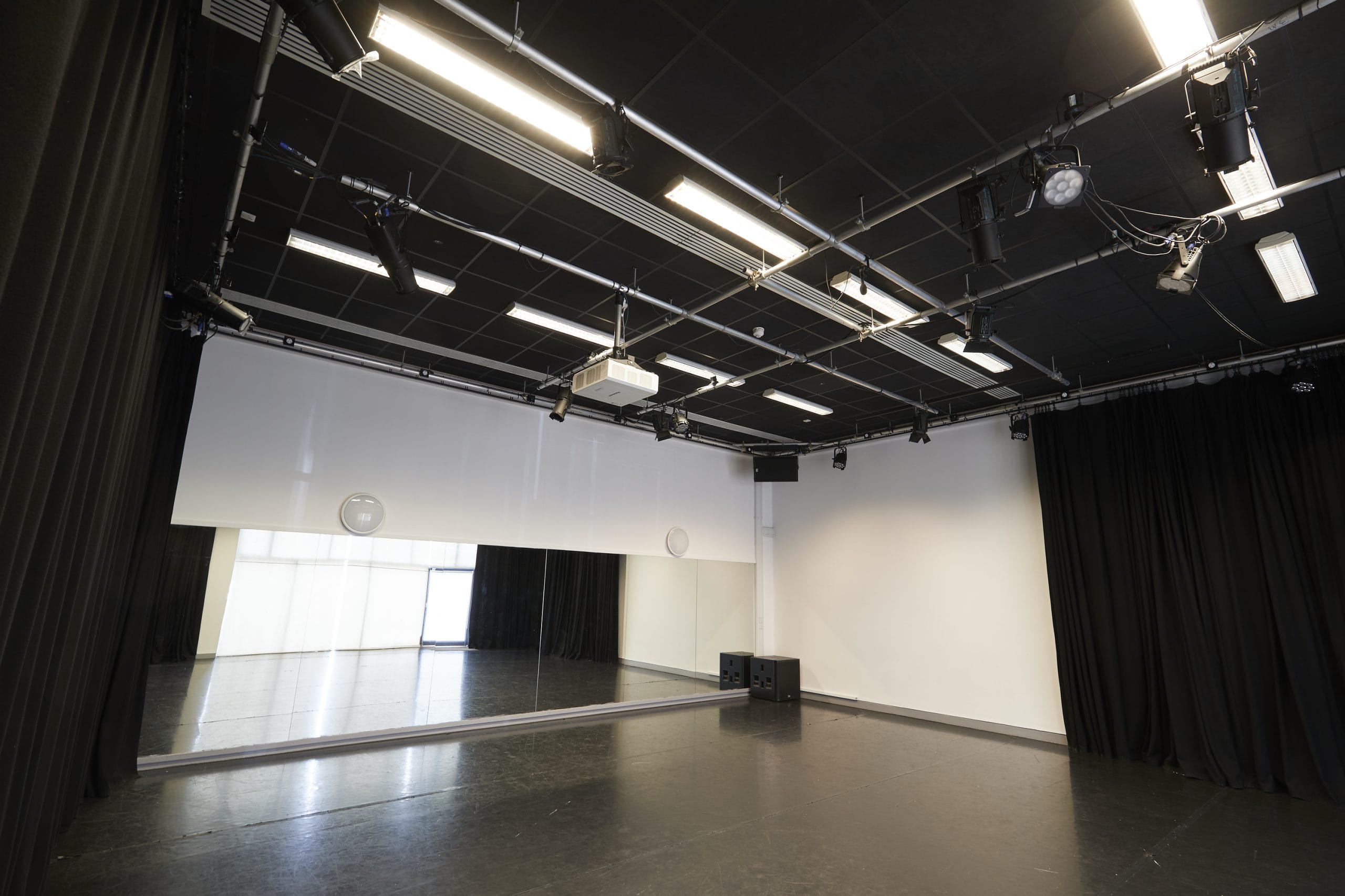 A black box studio space with mirror