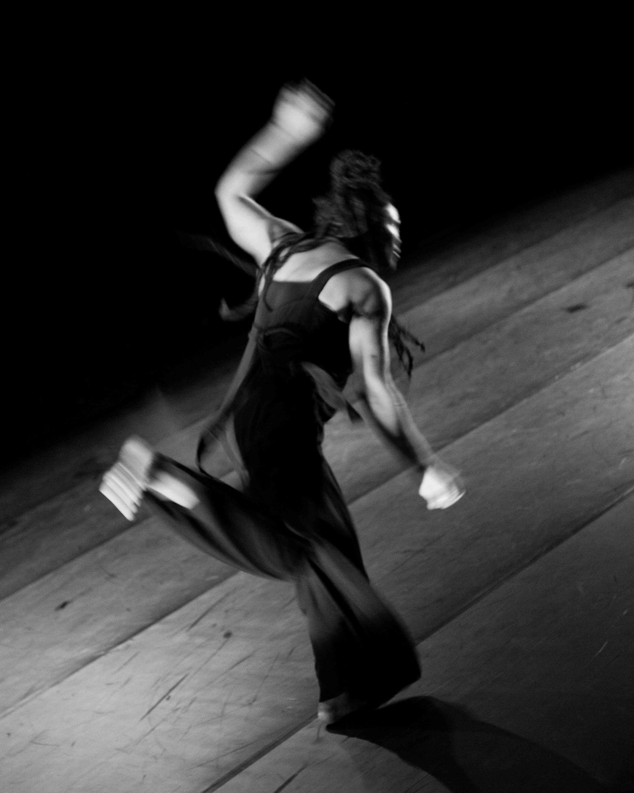 A black and white photo of a man in movement on stage