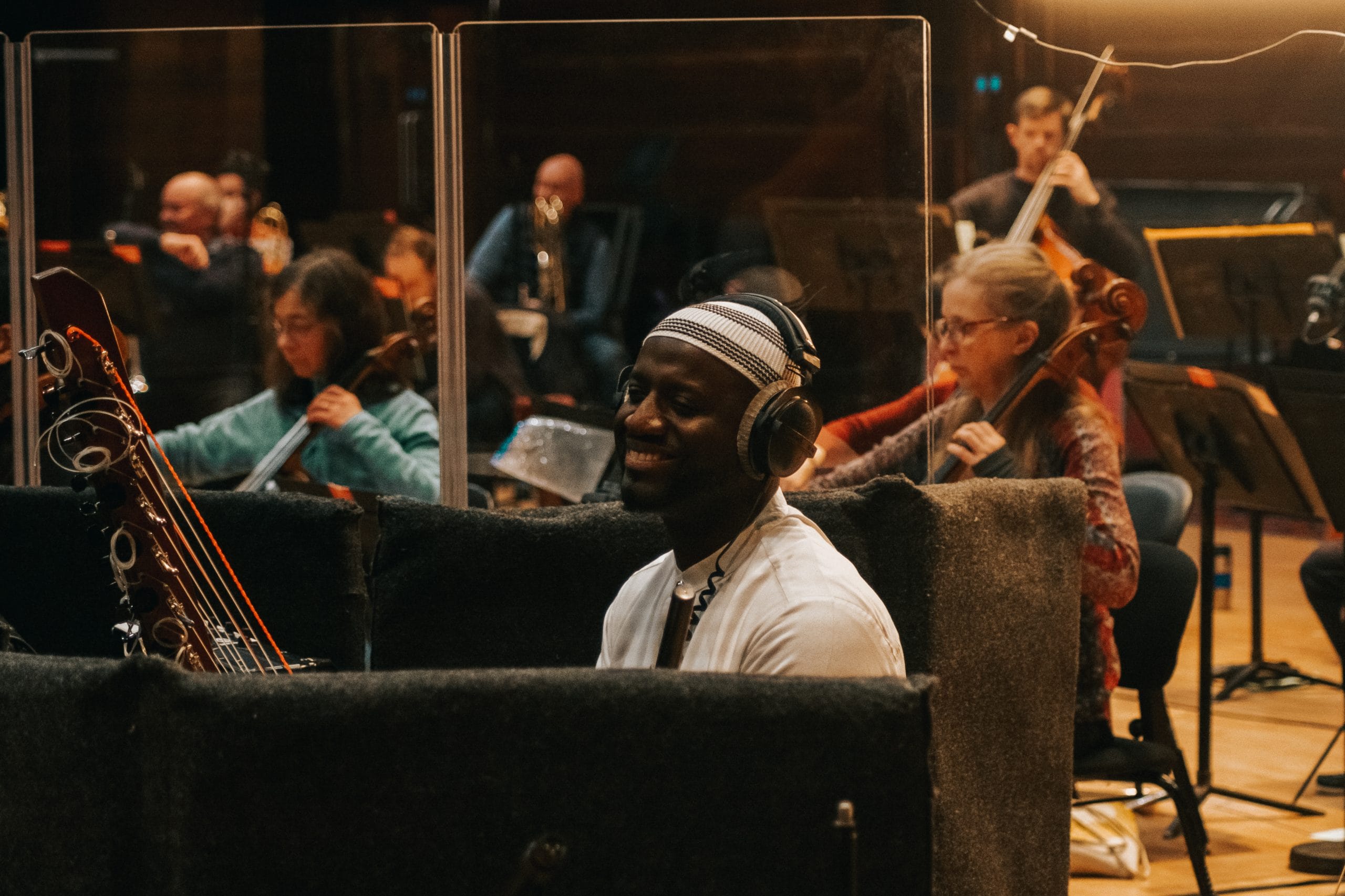 Sekou Keita, a musician, sits surrounded by an orchestra with headphones on