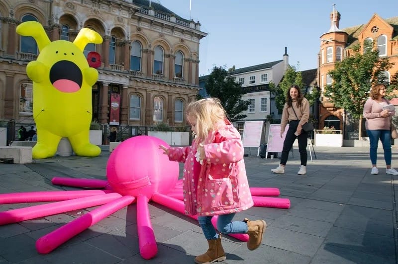 Children jump over an inflatable pink octopus