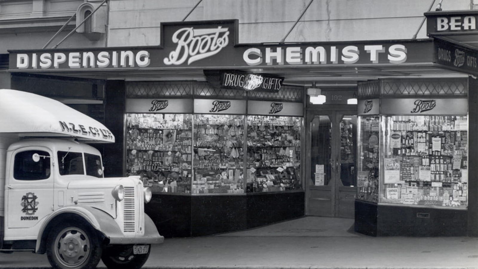 A black and white photo of a Boots chemist store in New Zealand