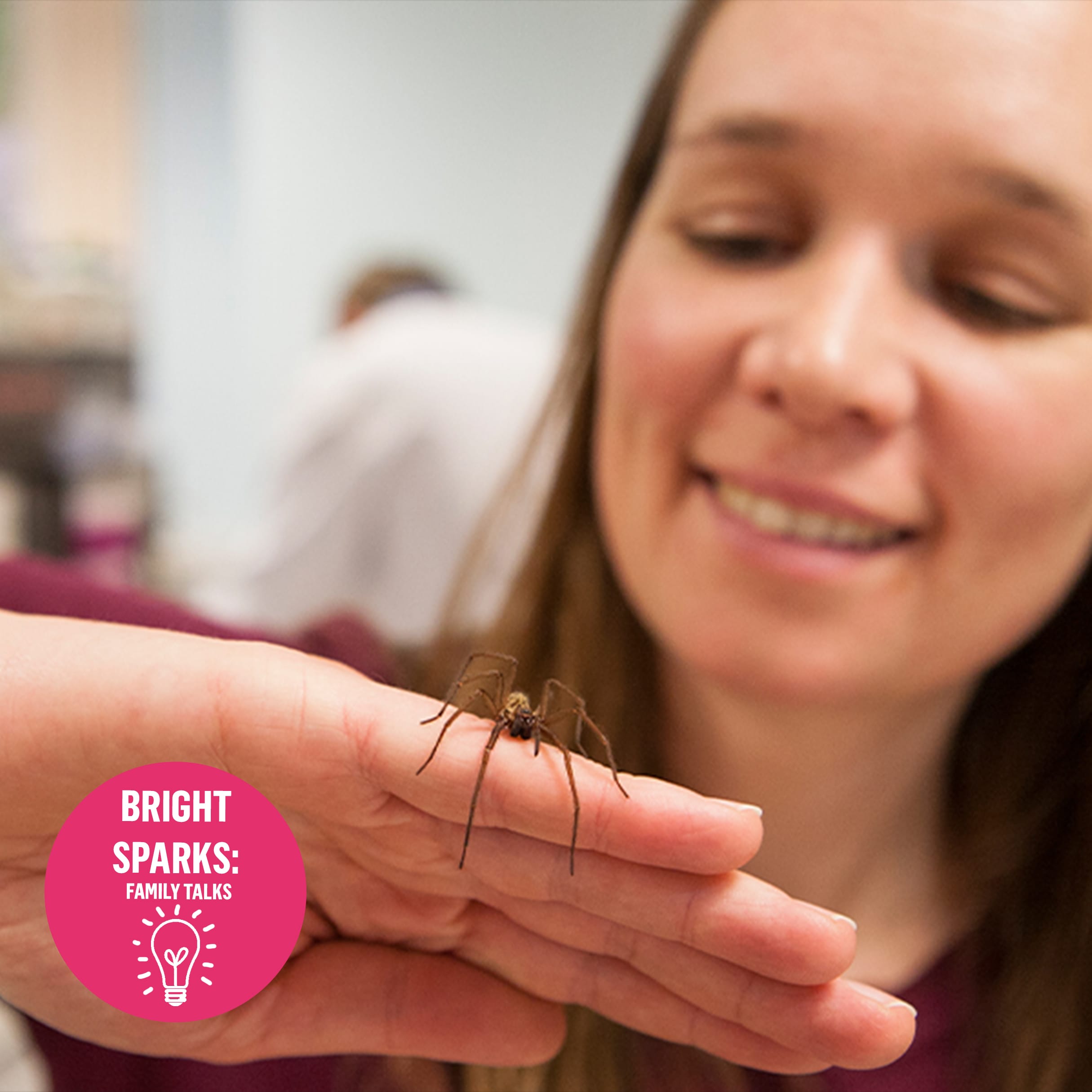 A woman holding a spider on her hand with a badge over the top that says bright sparks family talks