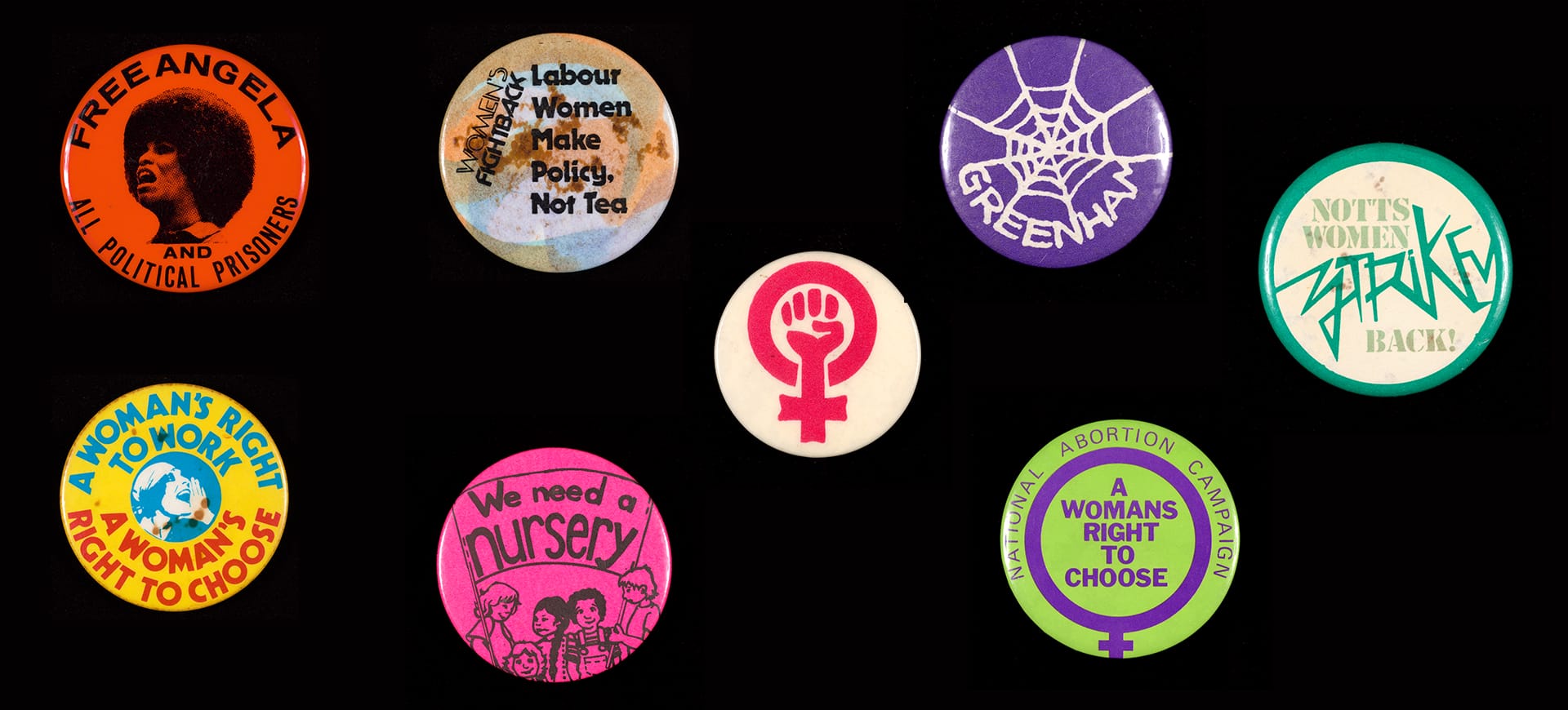 A collection of feminist badges on a black table