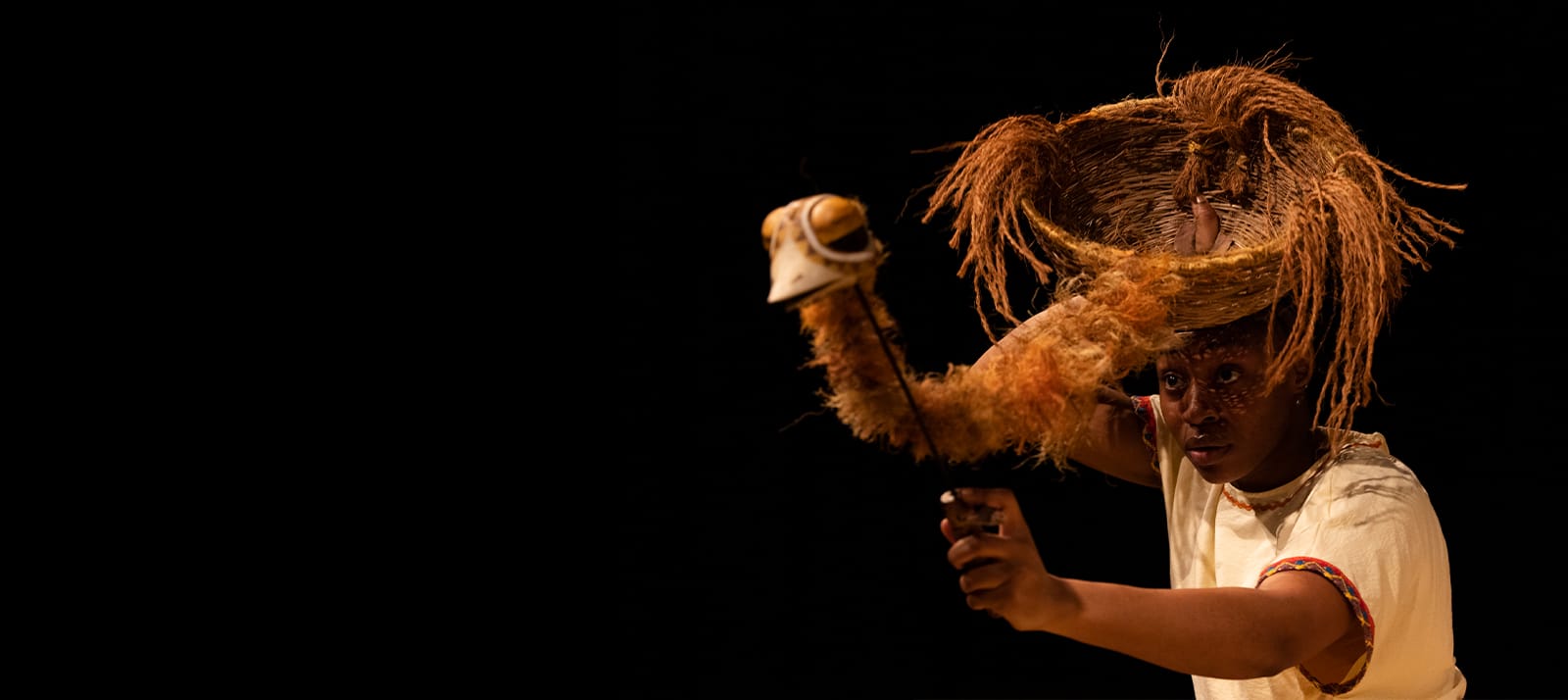 A woman wears a birds nest on her head and operates an emu puppet