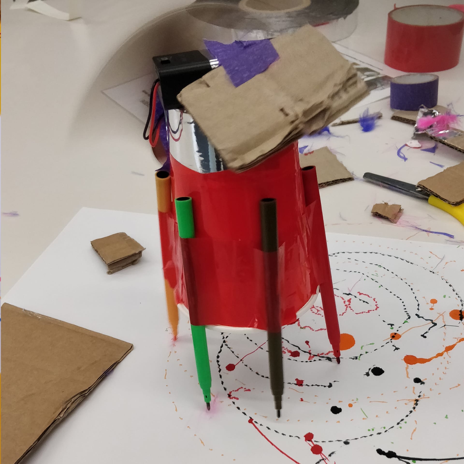 A cup attached to coloured felt tips and a motor to scribble by itself