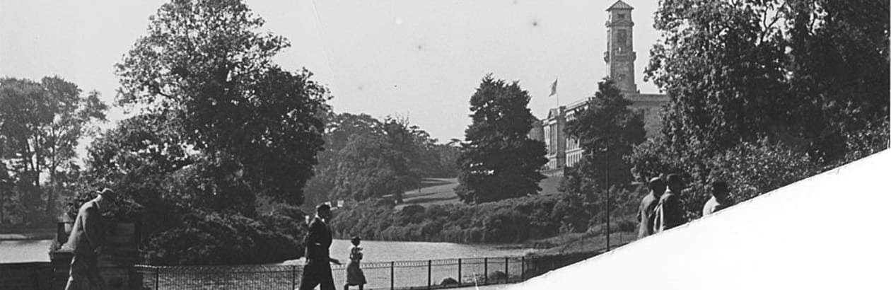 A black and white photo of Highfields Park with people in Victorian clothing walking