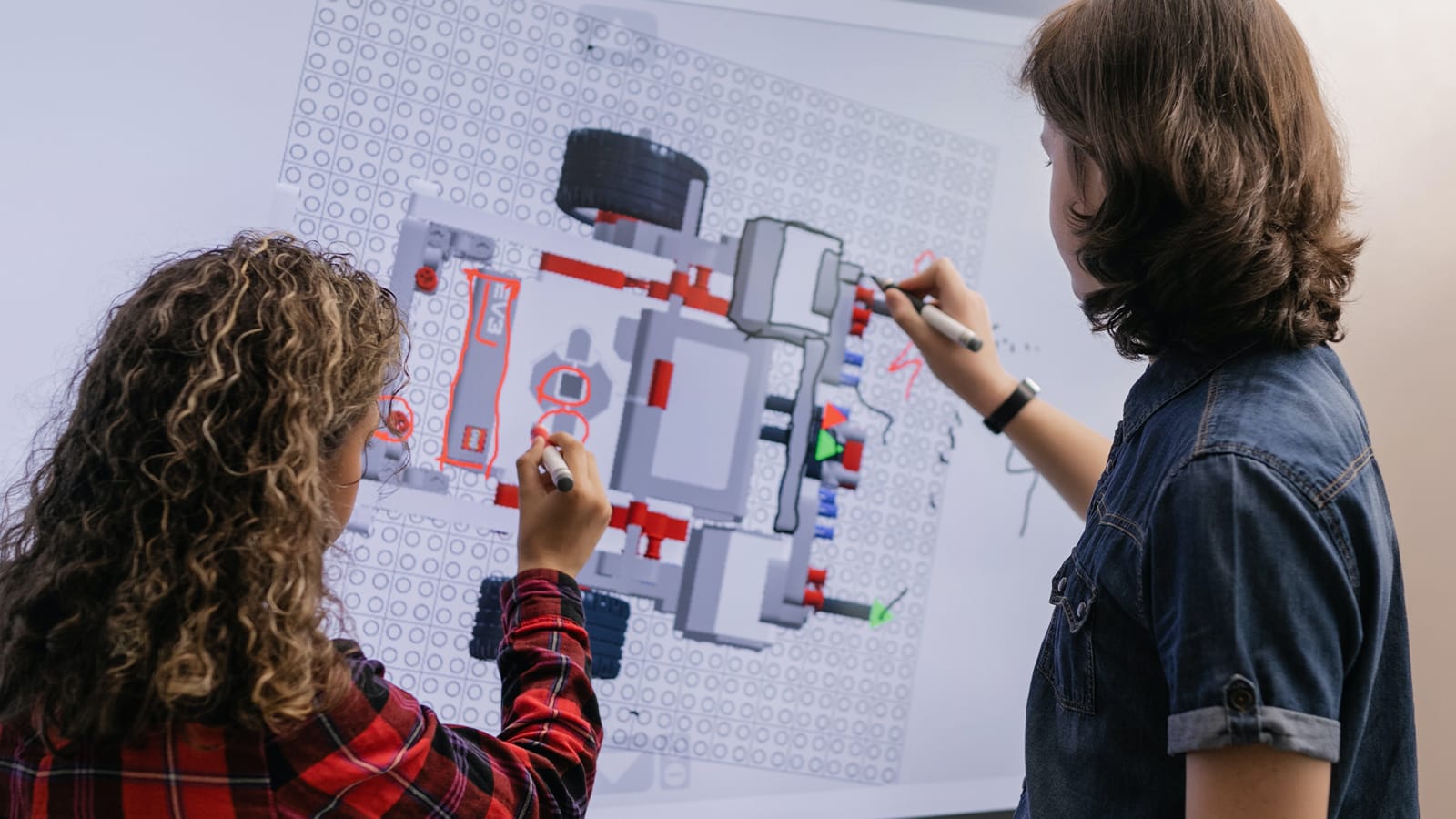Two teenagers draw on a model of an engine