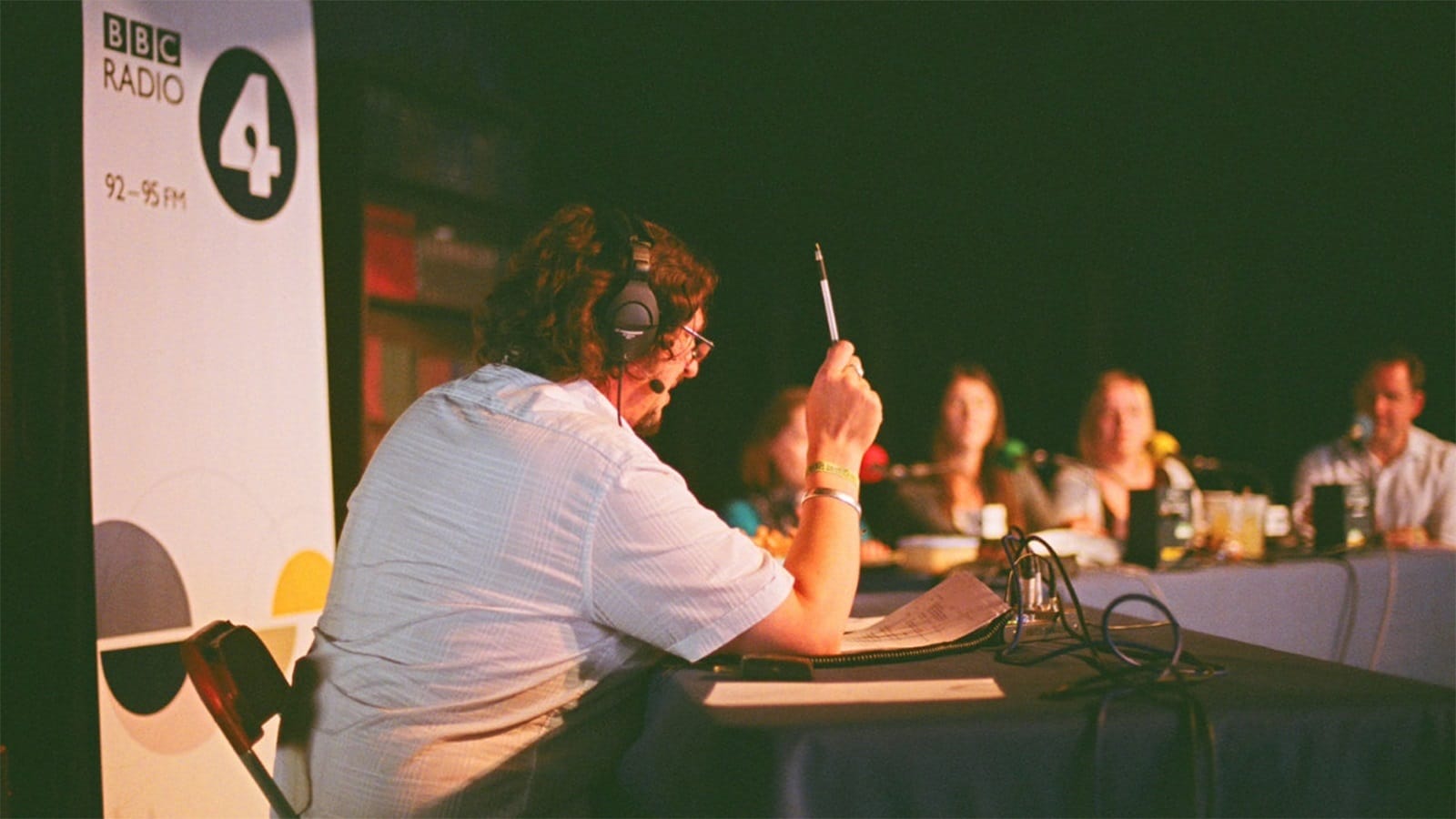 A man wearing headphones talks to a panel of people
