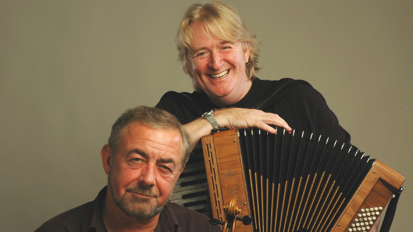 A man holding an accordion and a man holding a fiddle