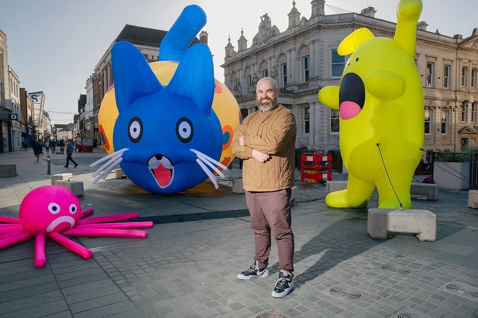 A man stands with colourful inflatables around him