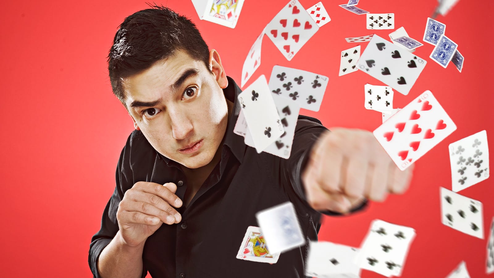 A man punches through a load of flying playing cards