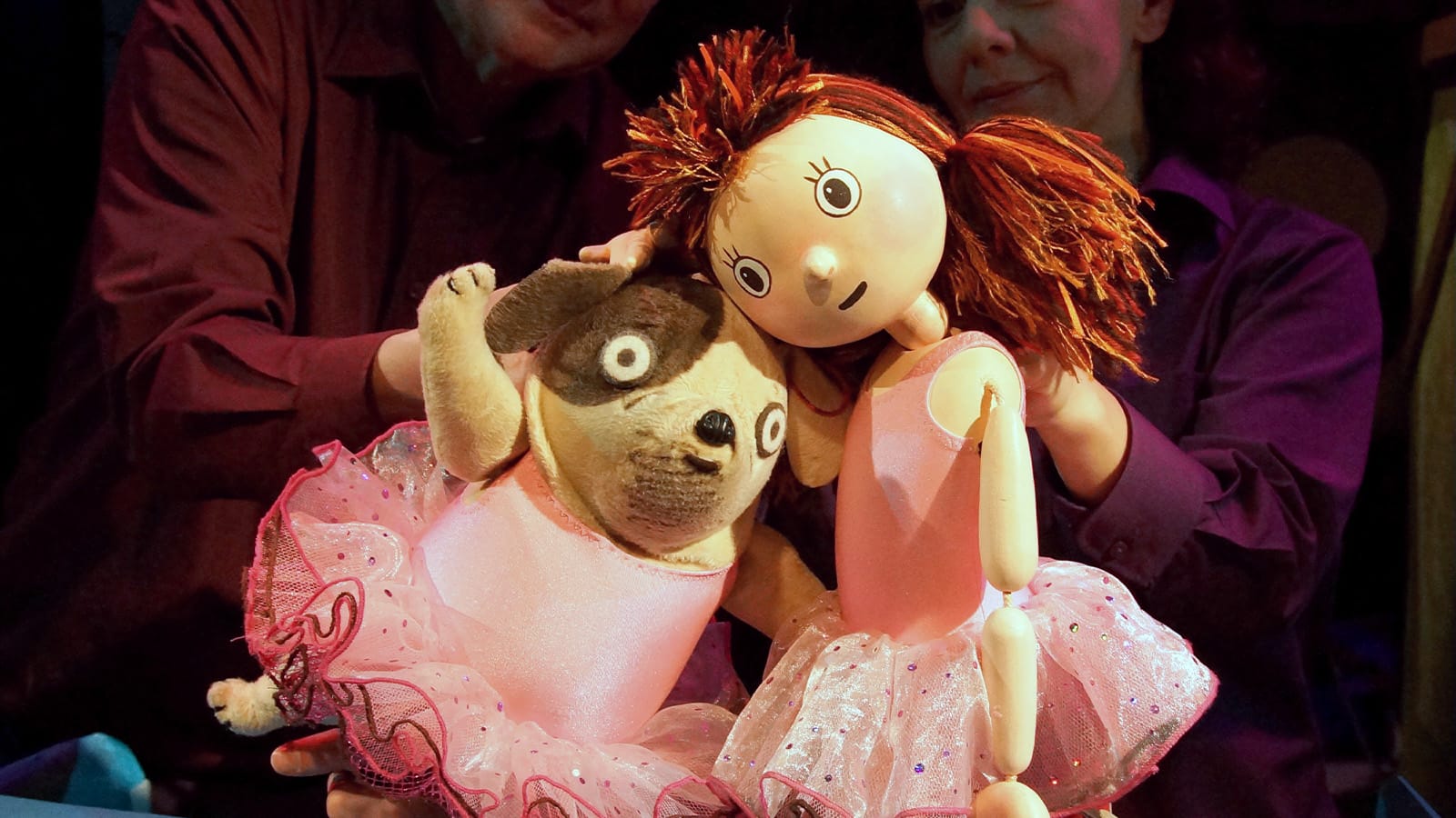 A puppet dog and girl in pink ballerina outfits