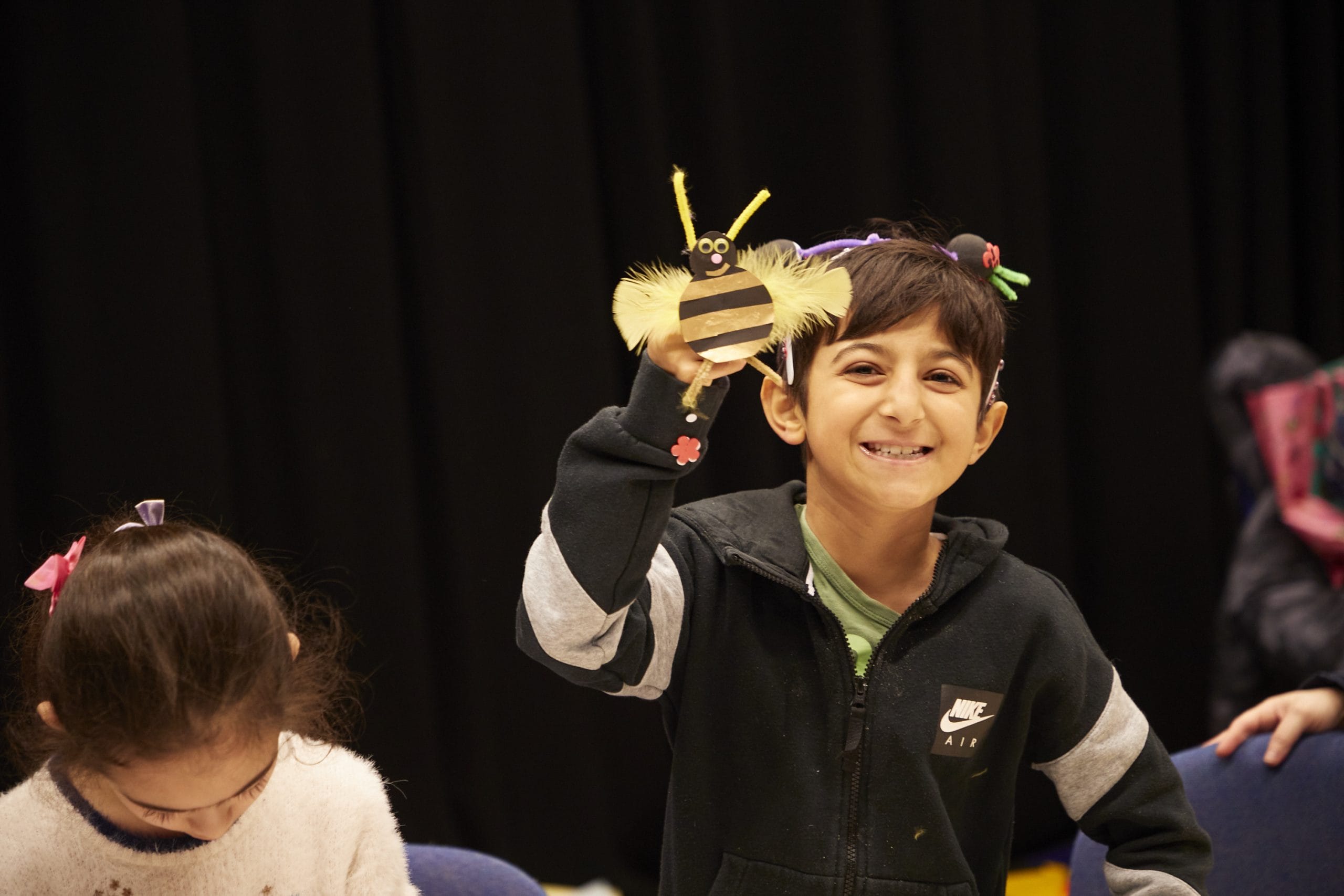 A boy holds up a handmade bumble bee