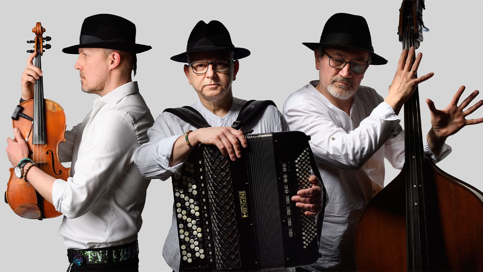 Three men in fedoras hold a bass, violin and accordion