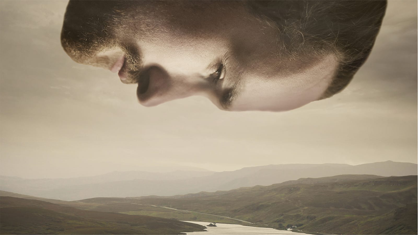 A man's head looking down on a hilly landscape