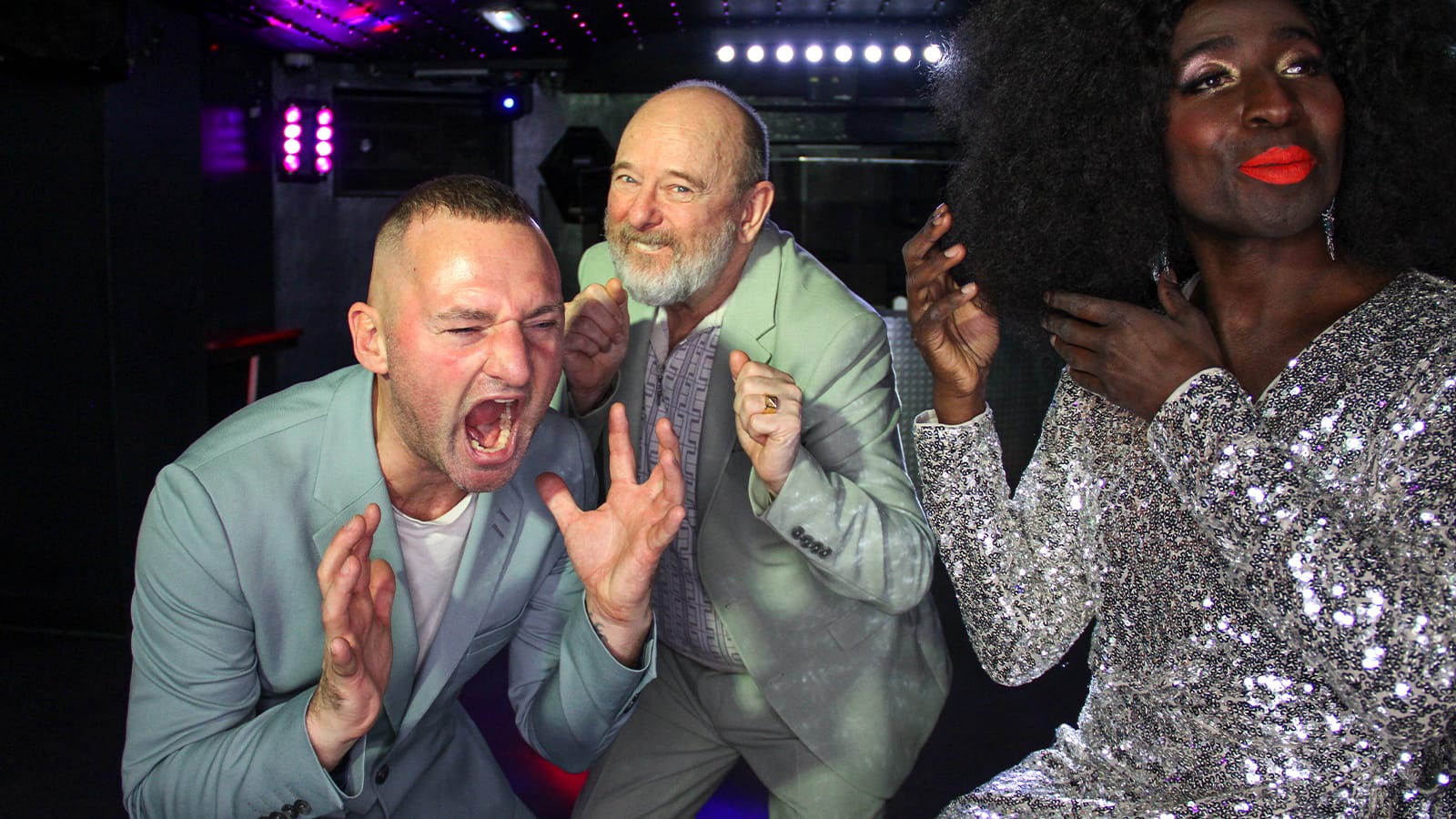 Two bald men in suits scream as a black woman combs her hair