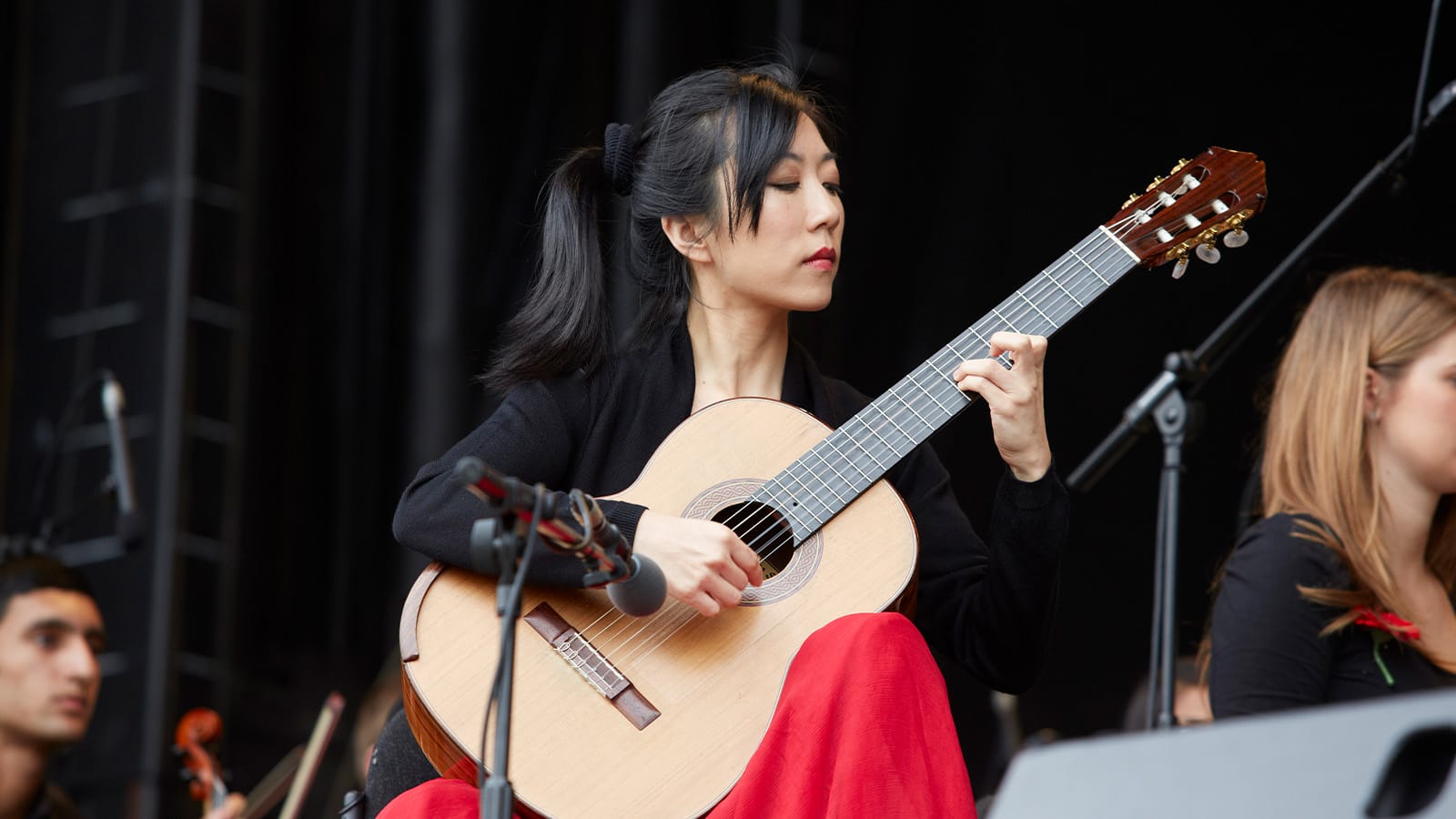 A woman in a red dress plays the guitar