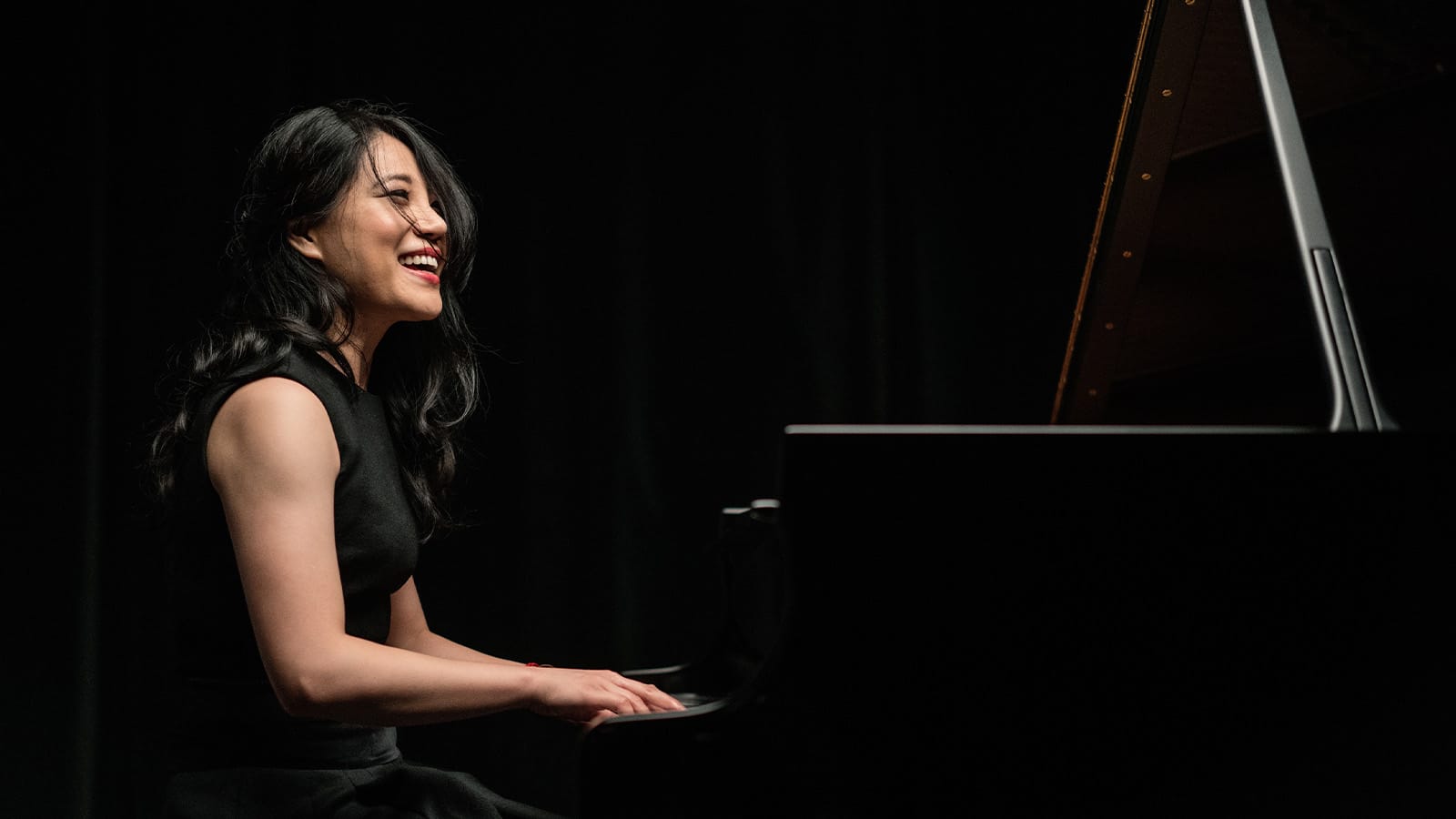 A woman with dark hair plays a piano