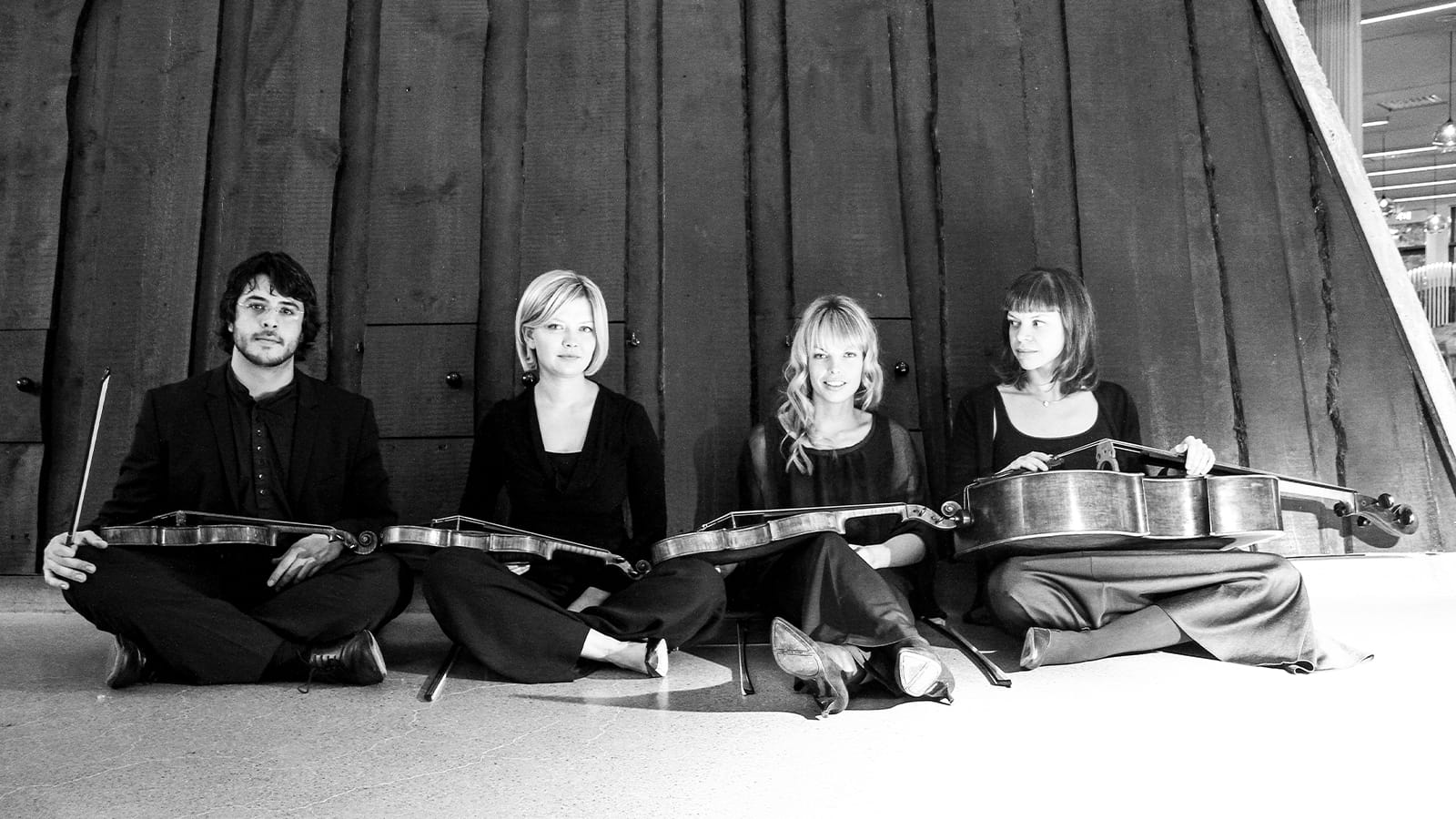 A black and white photo of four people sat with their instruments