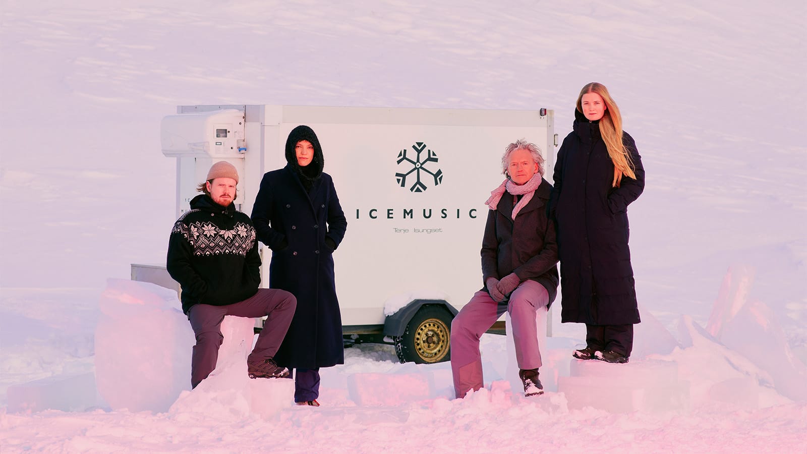 A group of performers stand in the snow with an ice tank