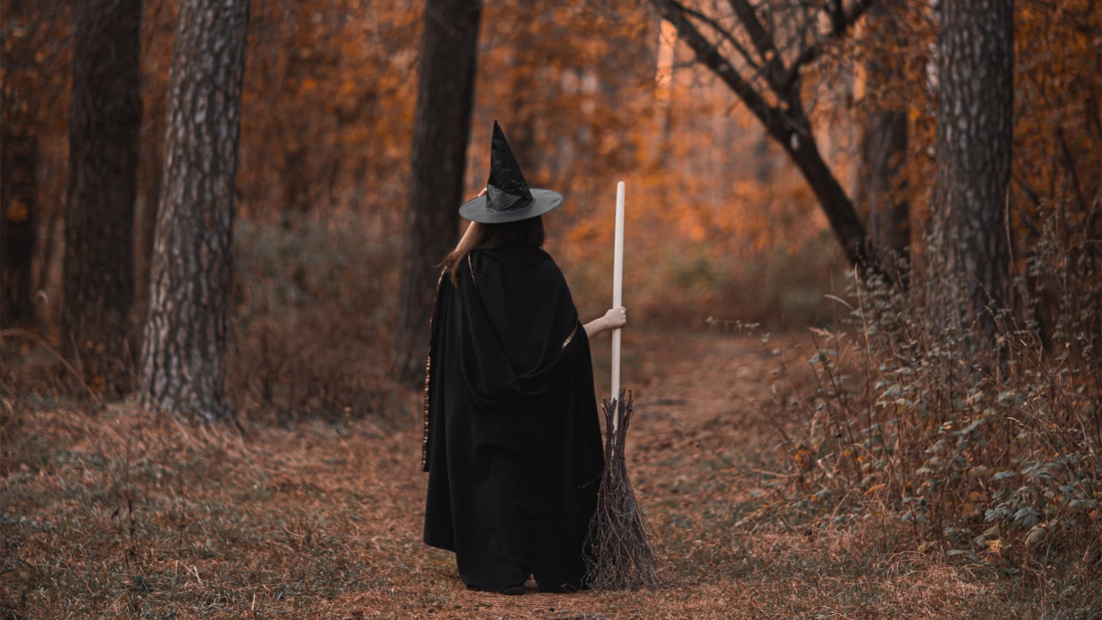 A witch walks through an autumnal forest
