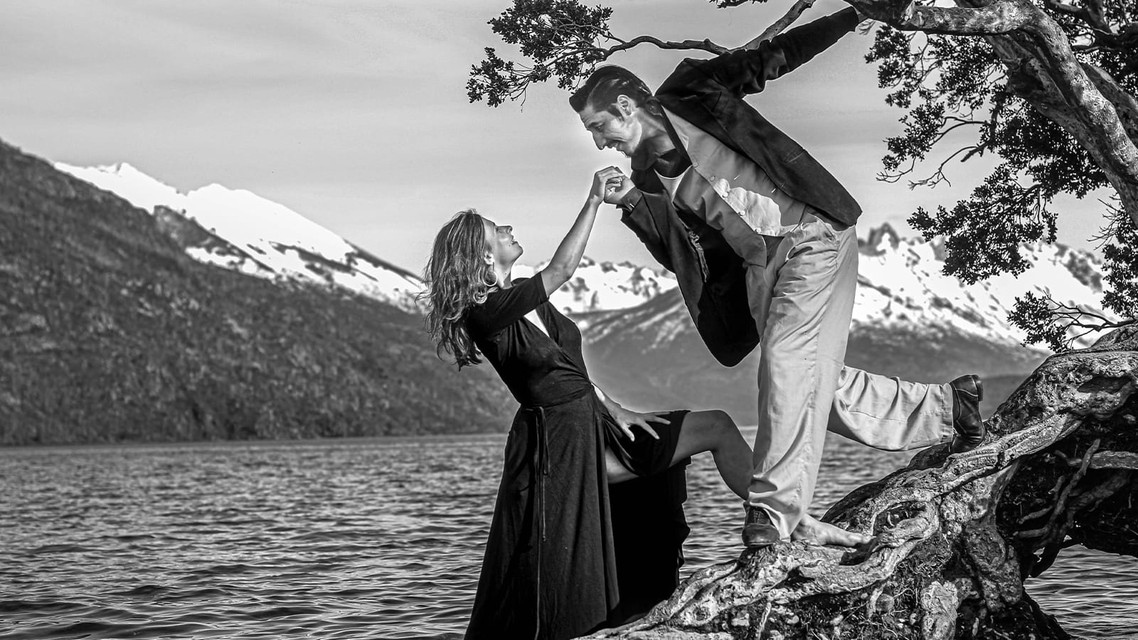 A black and white photo of two tango dancers leaning towards each other on a tree