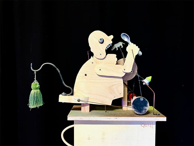 A wooden moving sculpture of a man eating