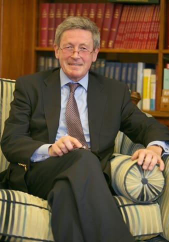 Sir Colin Campbell sitting in an armchair in front of a bookshelf