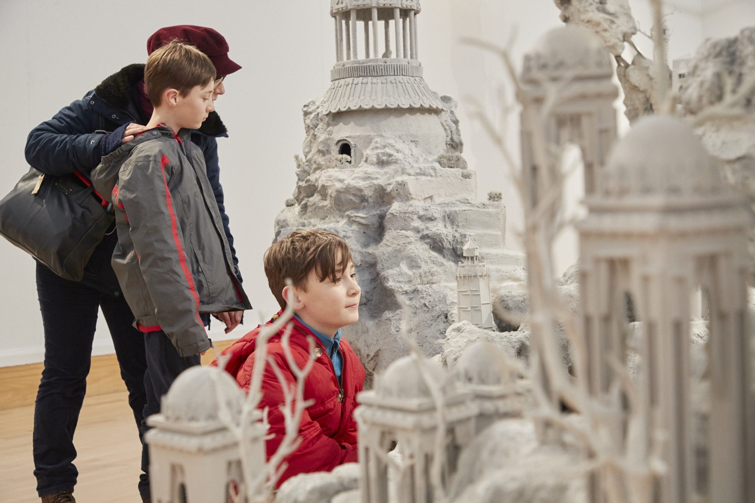 A child looks at a white sculpture of tiny houses