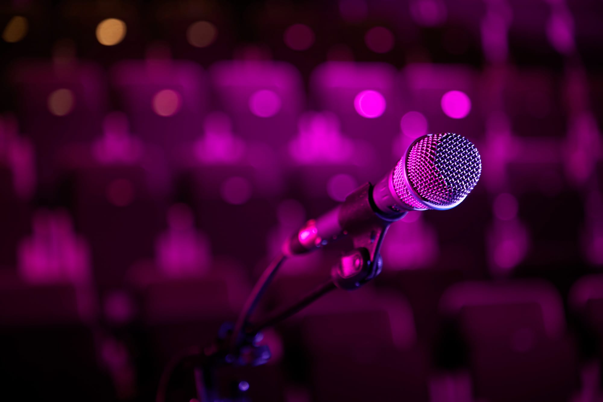 A close up of a microphone, lit pink.