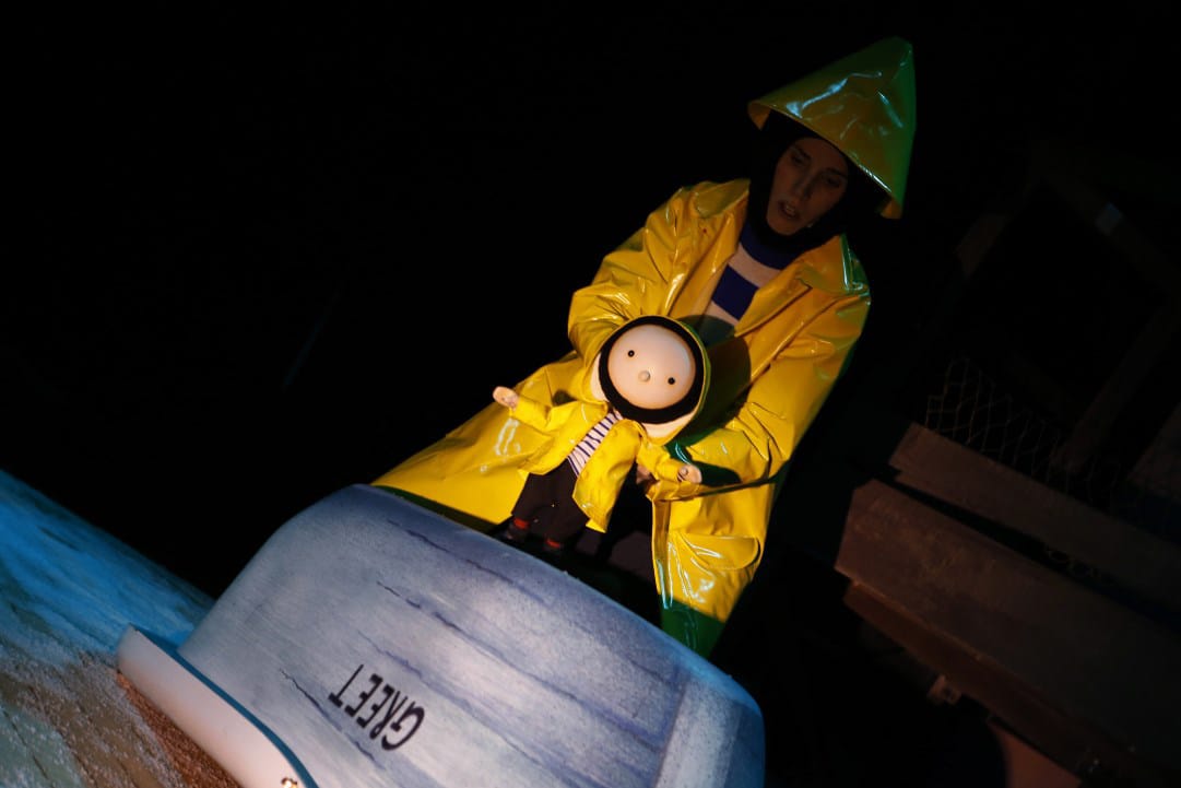 A puppet in a yellow raincoat sat on a boat