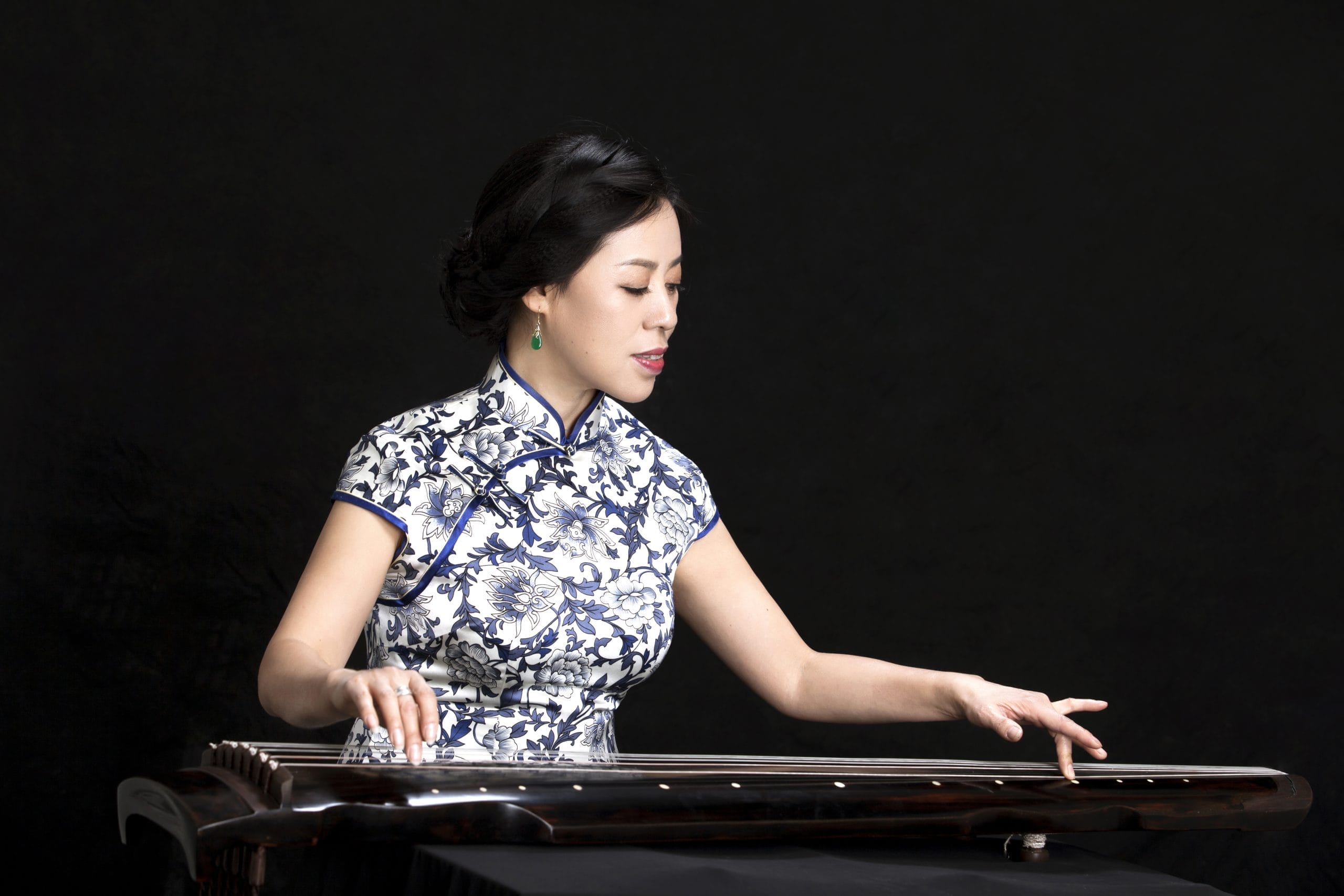 women playing instrument wearing Qipao.