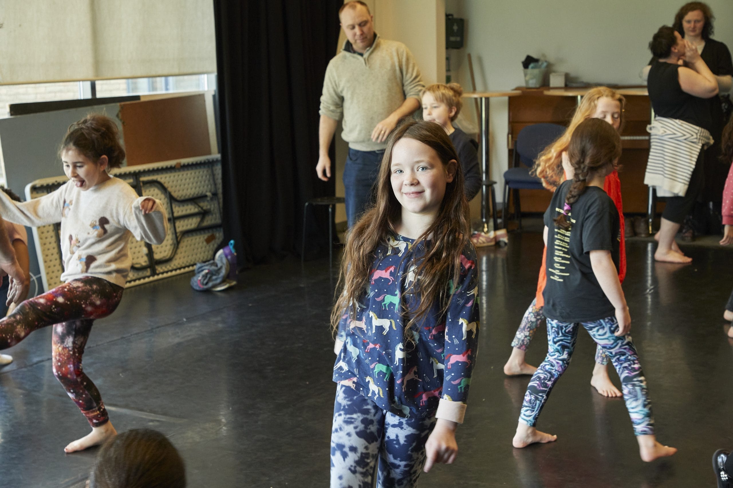 A group of children moving around in a performing arts studio