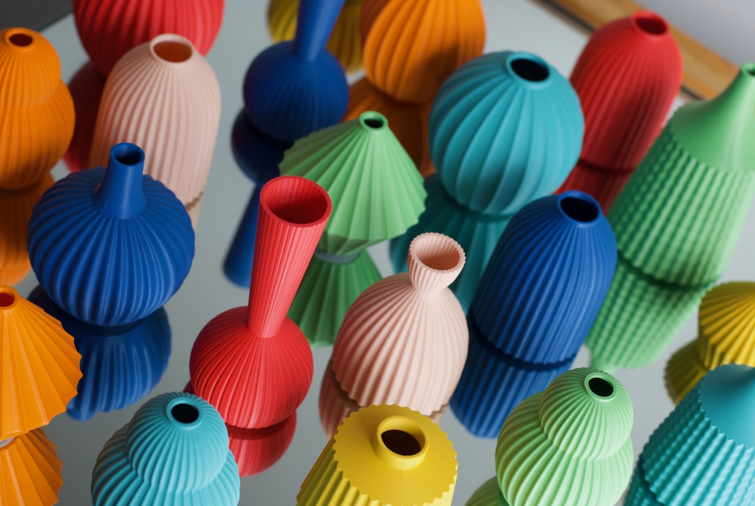 A selection of bright primary coloured pots sit on a mirrored surface