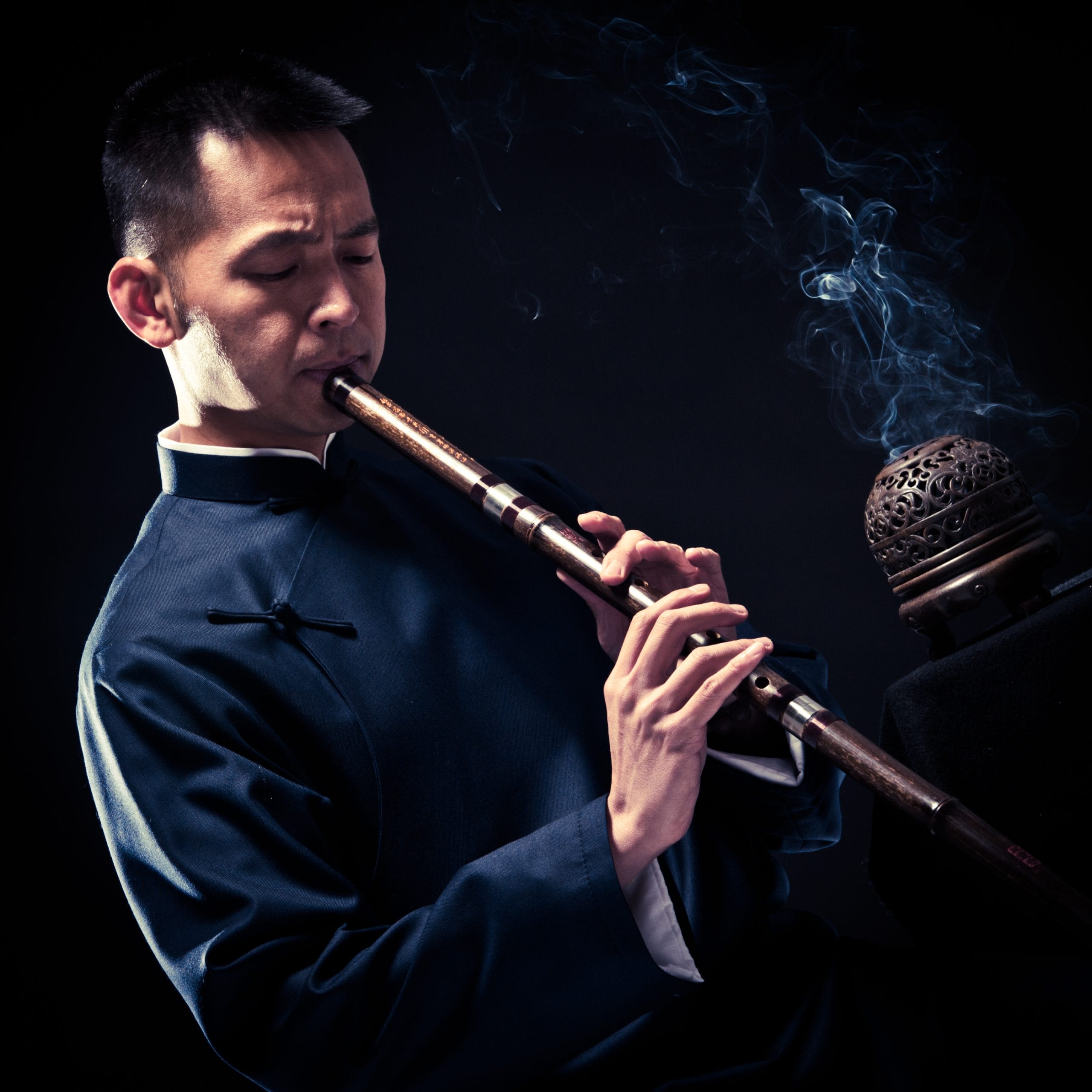 MAN PLAYING FLUTE WITH BLACK BACKGROUND