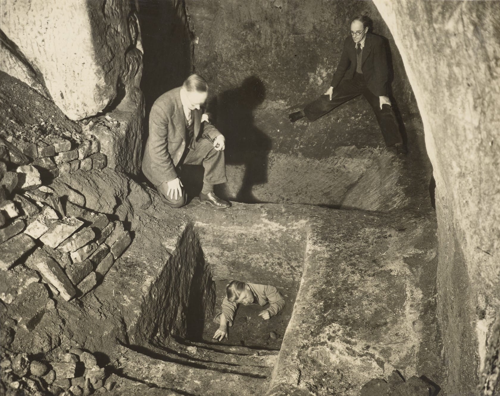 A black and white photo from 1951 shows 3 men exploring underground caves