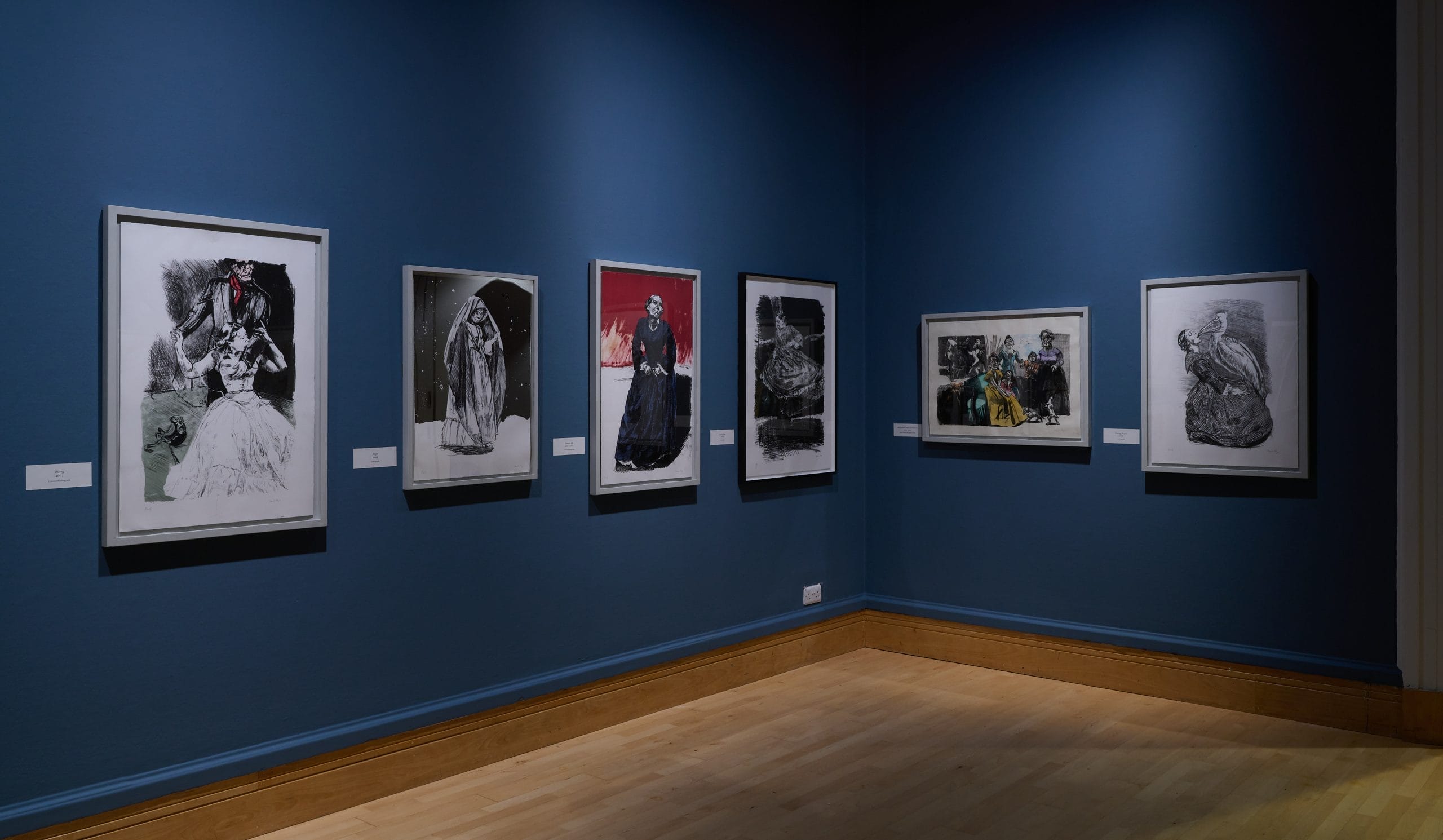 The corner of a gallery space, with walls painted blue and wooden floors. Prints by Paula Rego, inspired by Jane Eyre, hang on the walls.