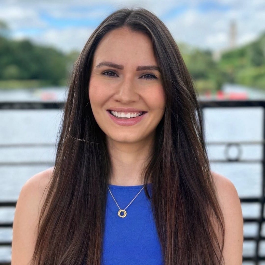Woman in blue with dark hair in front of lake