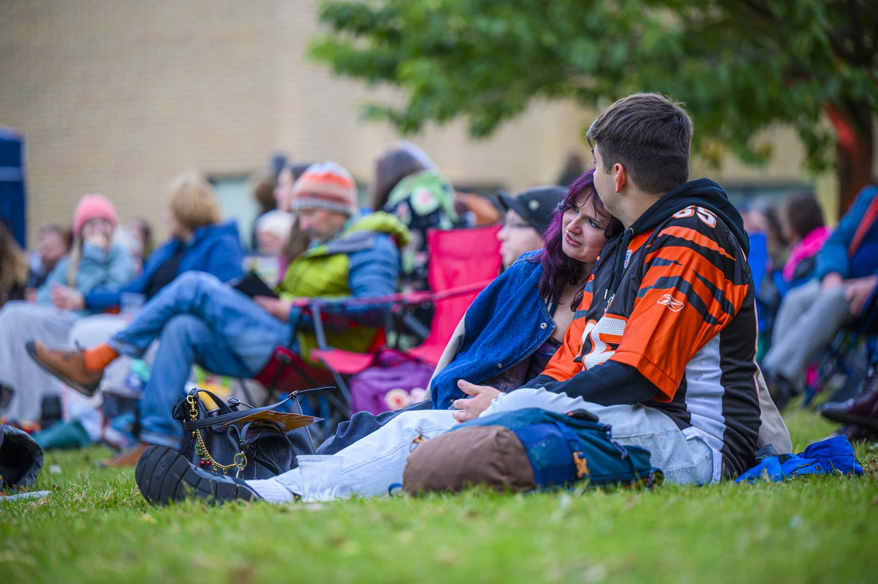 audiences are sitting on the grass and camping chairs while watching outdoor cinema at Lakeside Arts