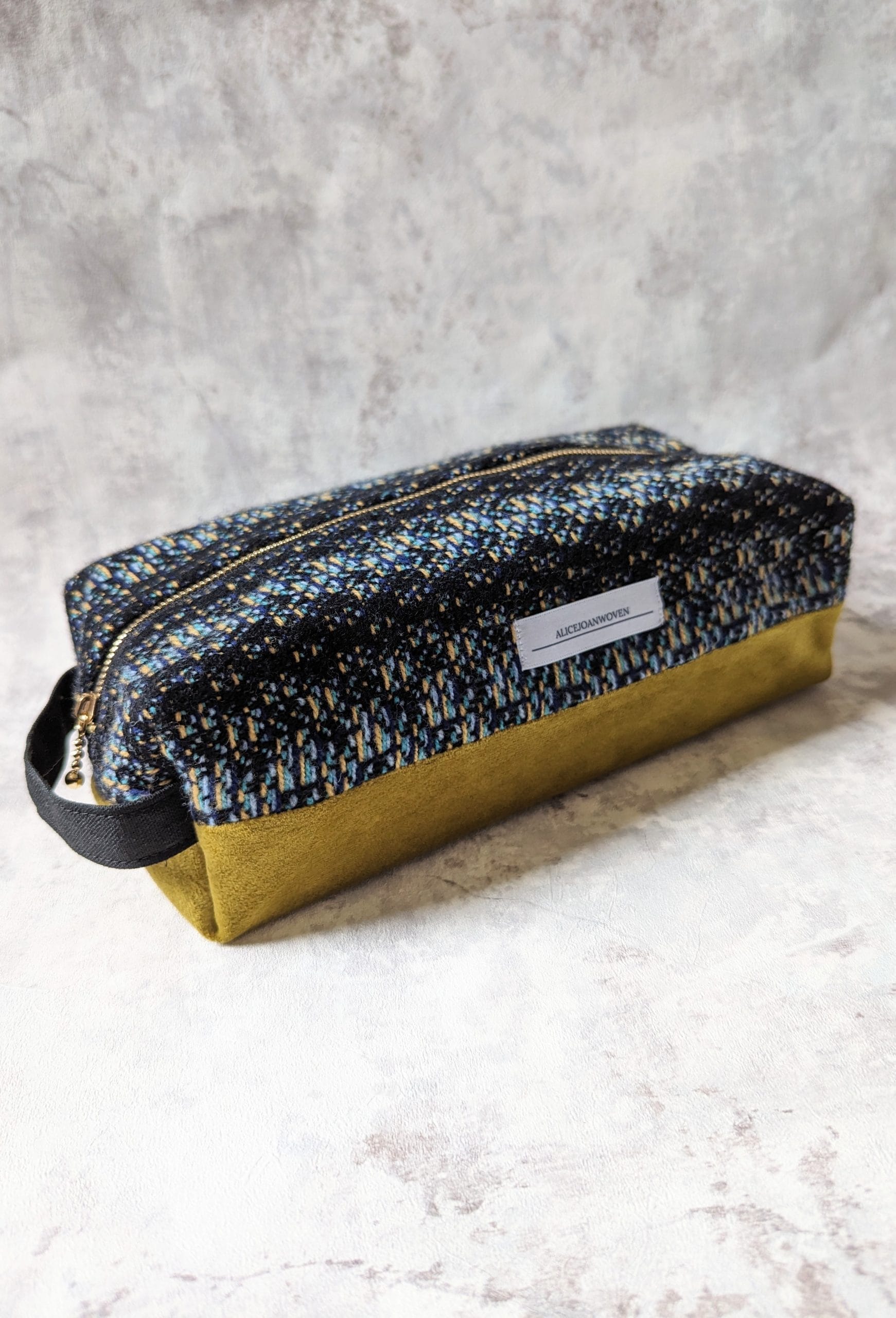 a small woven zip bag. The bag is patterned and has yellow running across its base.