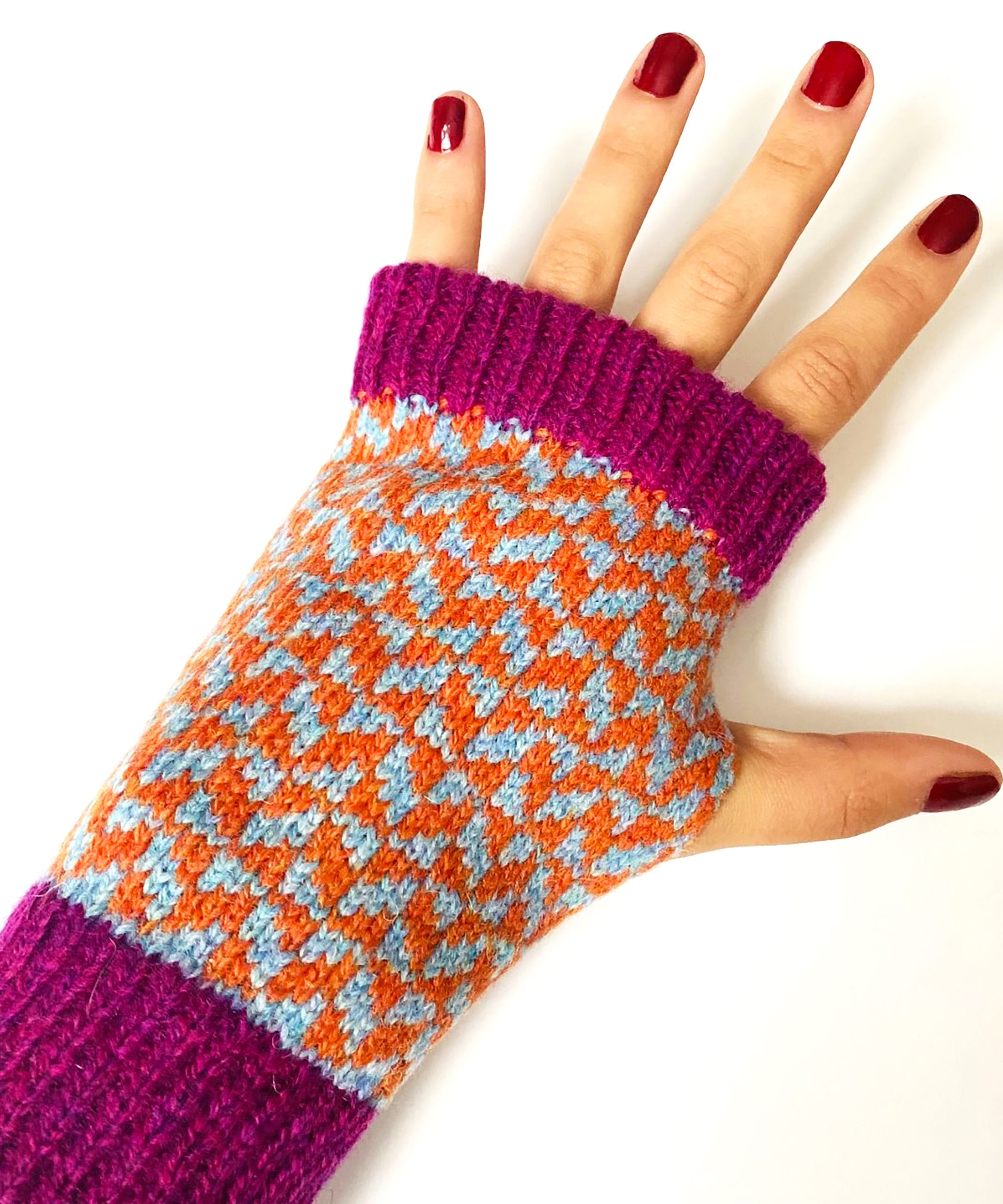 a hand wearing a knitted fingerless purple and orange gloves