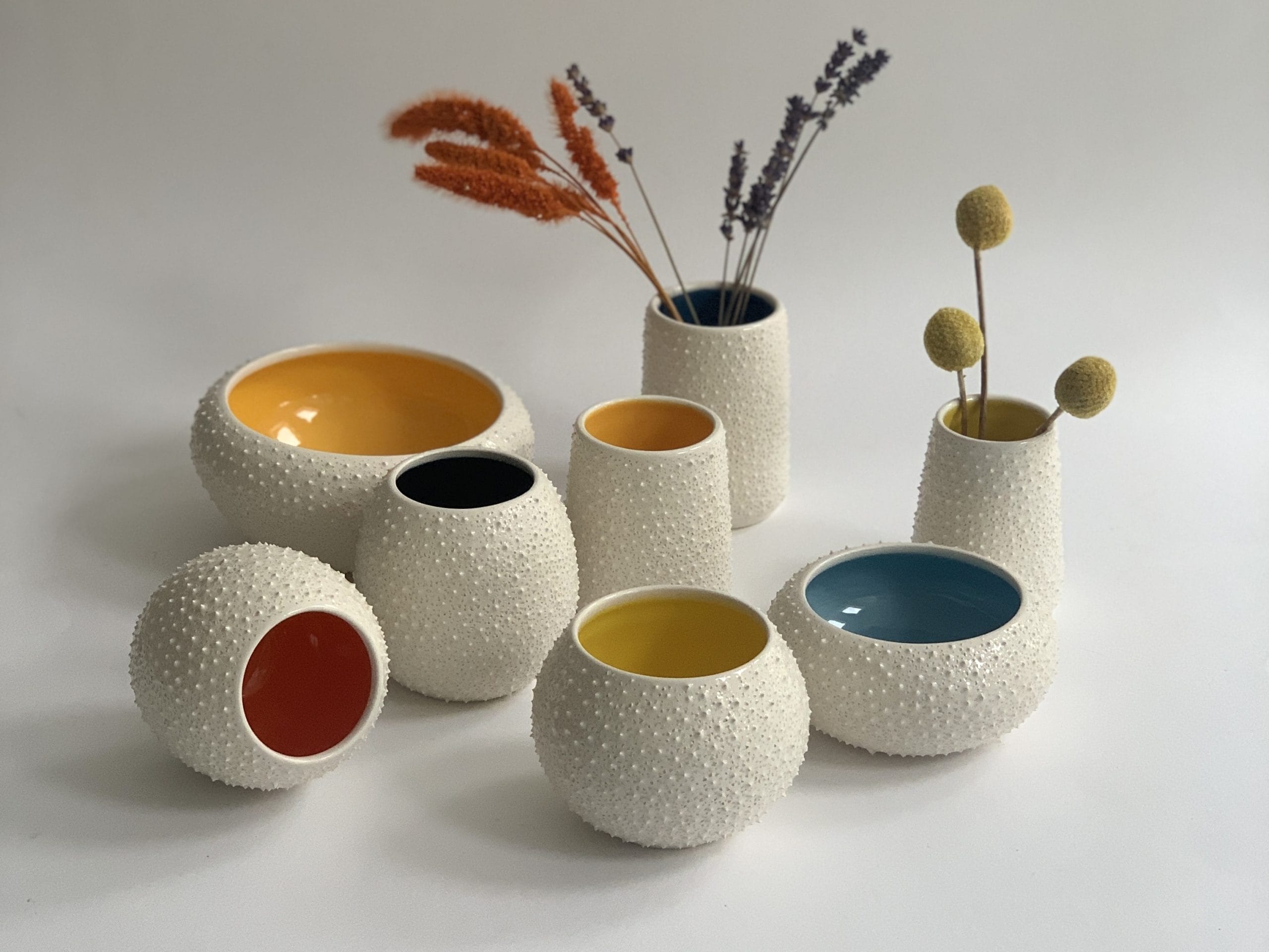 A selection of cream ceramic pots with different coloured interiors