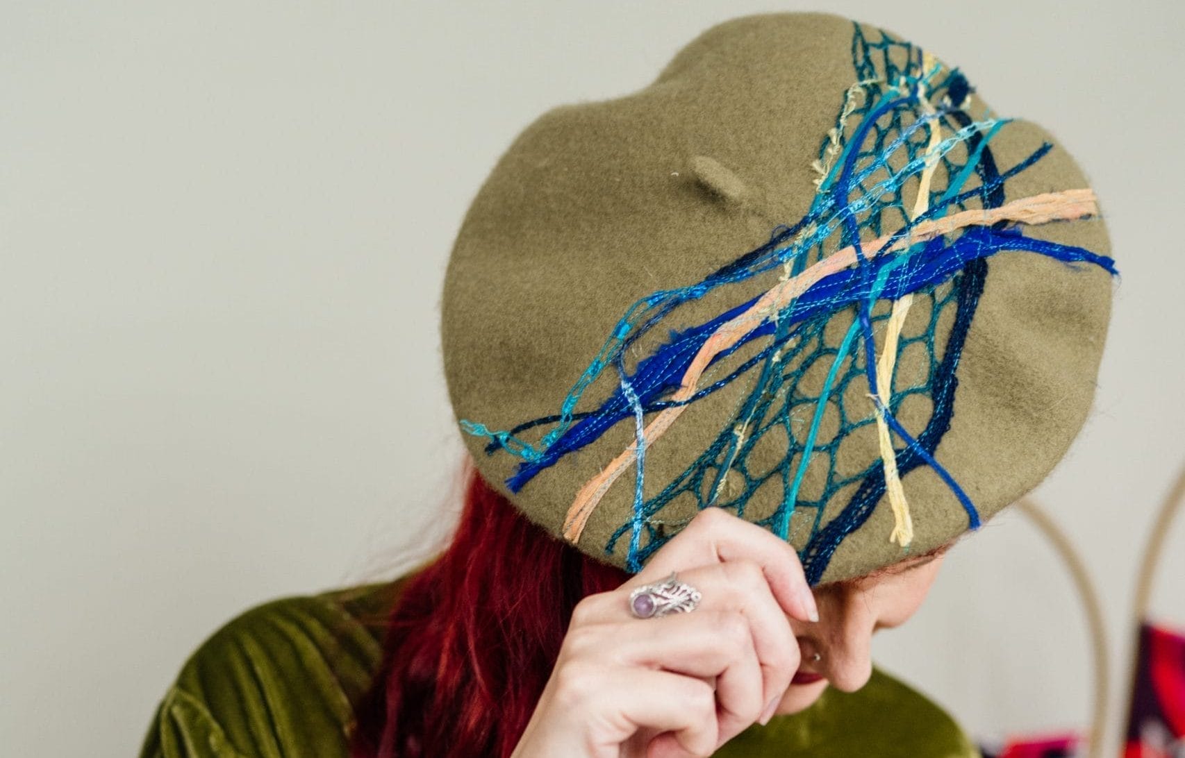 Red haired lady modelling a green and blue patterned hat