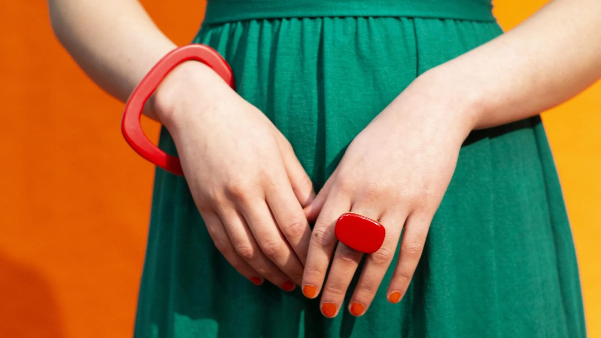 a person wearing an orange bracelet and a red ring